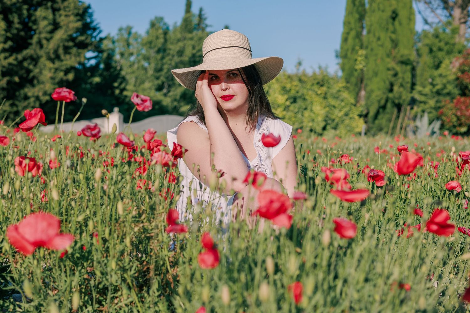 Une femme pose dans un champ de coquelicots pendant une séance photo portrait en extérieur.