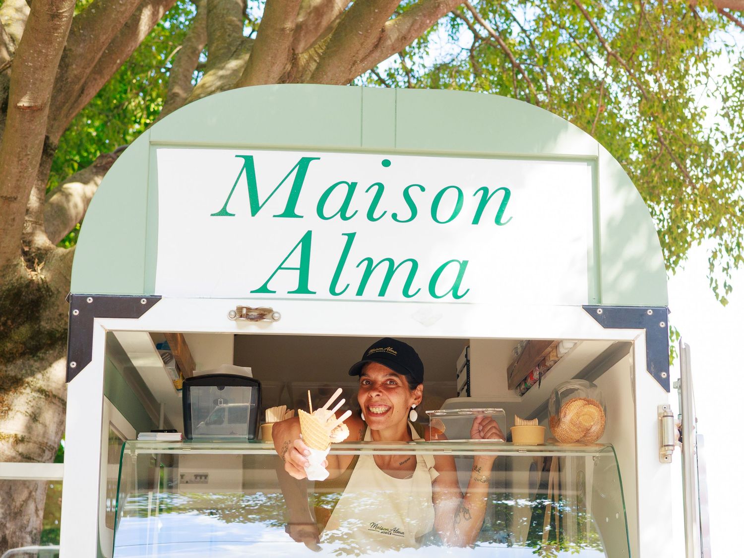 Une femme sourit depuis le camion de glace Maison Alma lors de son inauguration.