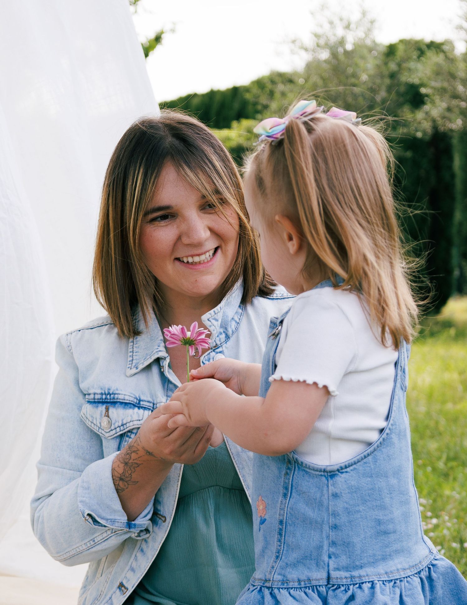 Une maman pose avec sa fille pendant une séance photo famille en extérieur.