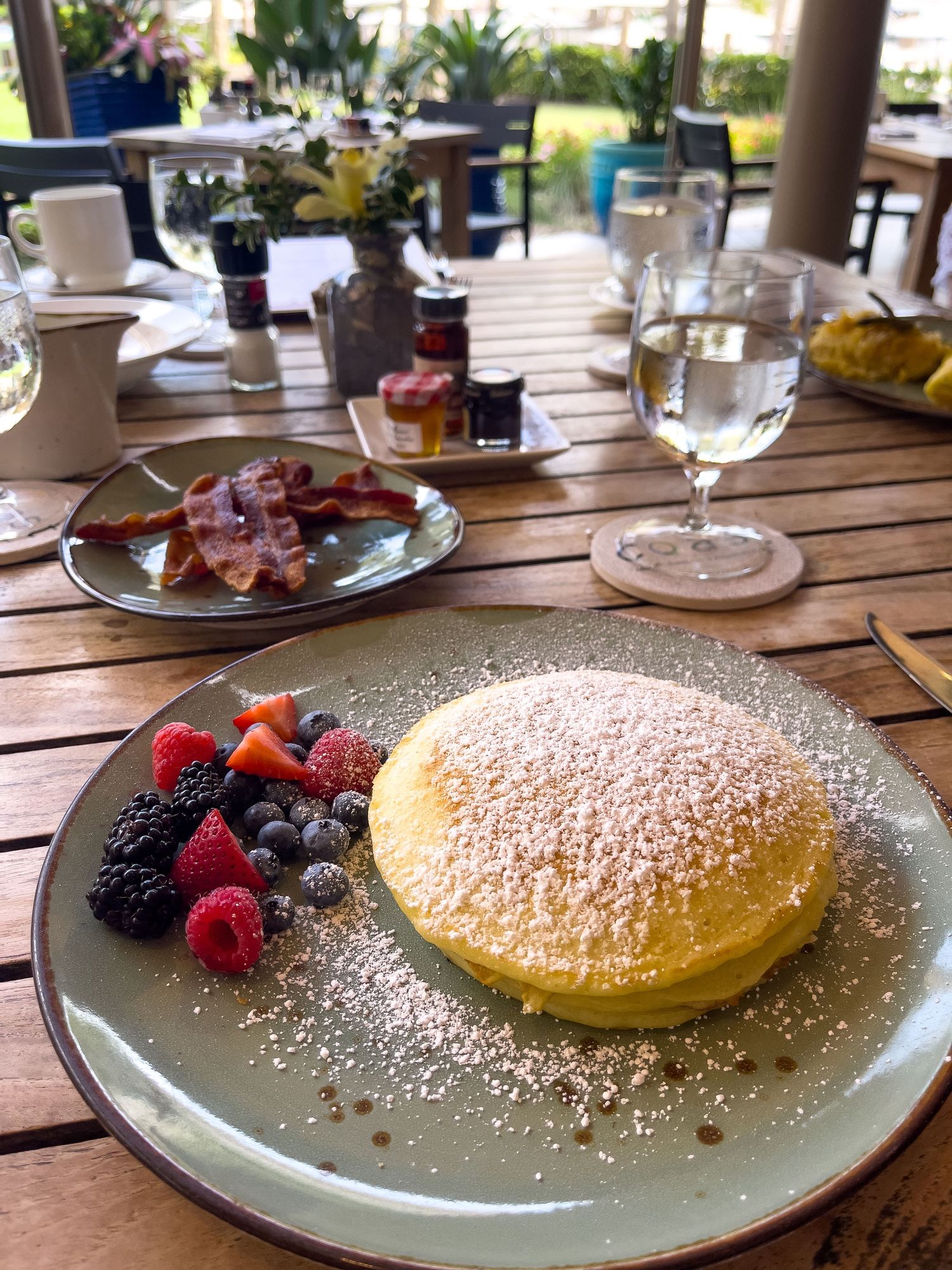 A fluffy Japanese souffle pancake dusted with powdered sugar and served with fresh berries on a gray plate at a restaurant.
