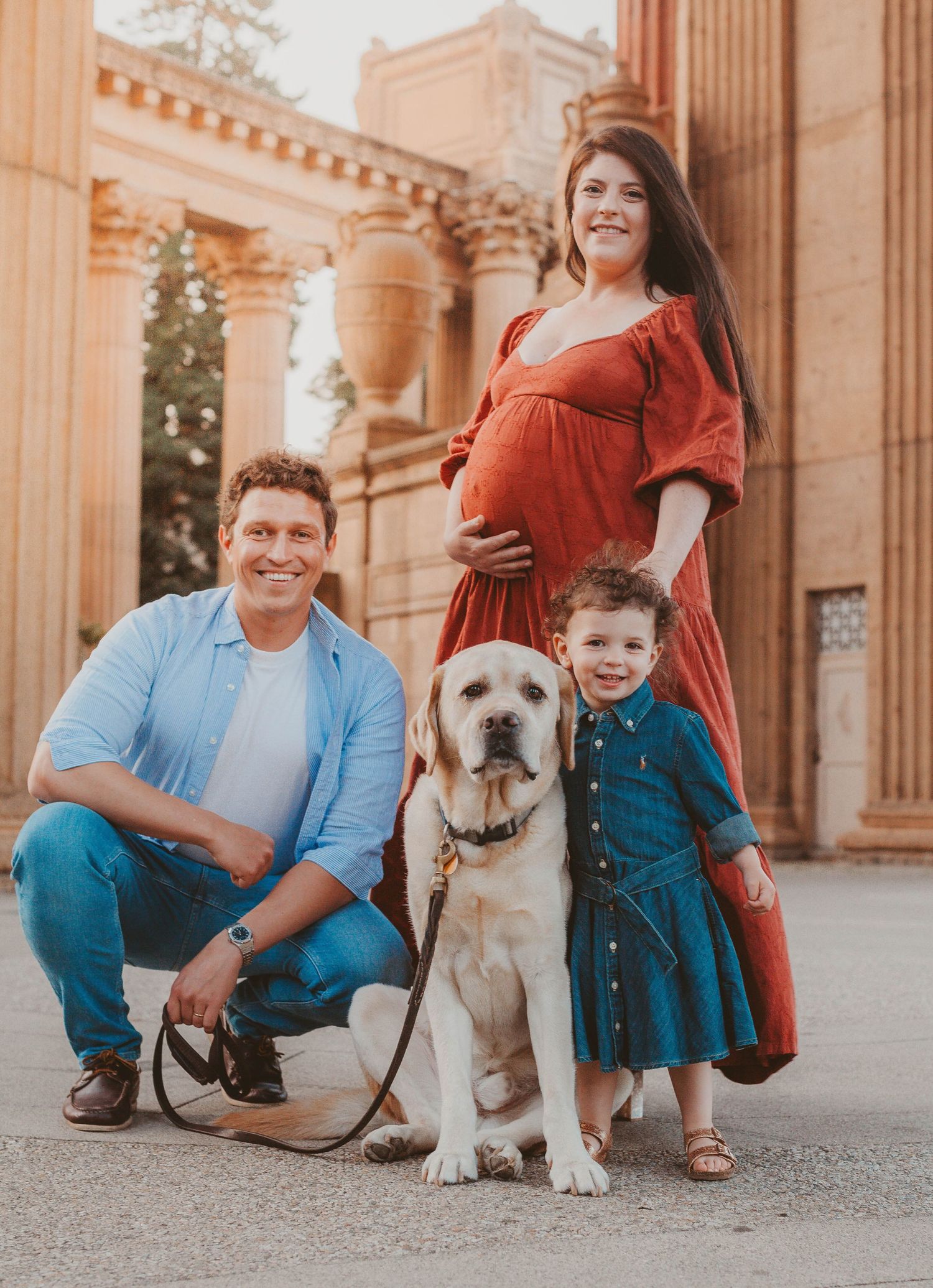 Smiling family with pregnant mother, father, toddler, and yellow lab at Palace of Fine Arts.