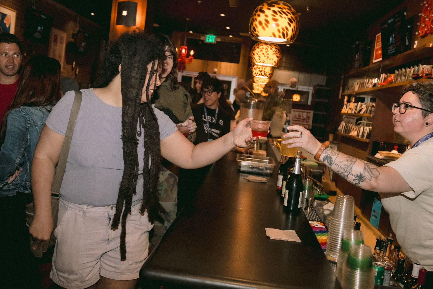 Bartender serving drinks to guests at a lively Frameline LGBTQ film festival after-party bar event.