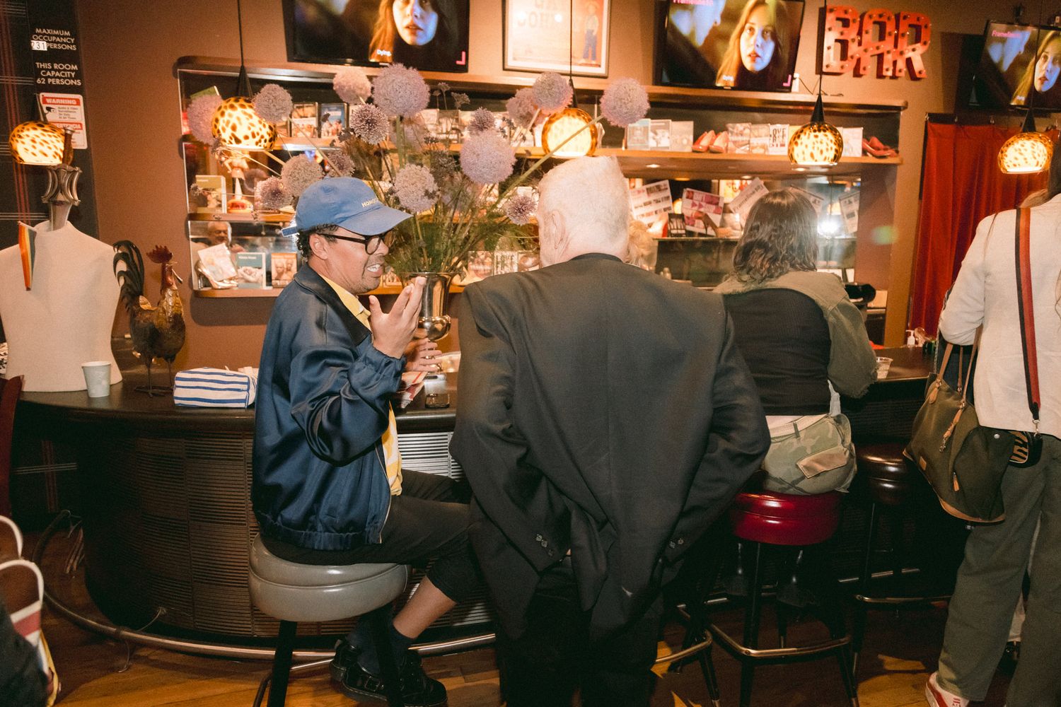 People socializing at a warmly lit bar with vintage decor and memorabilia on display.
