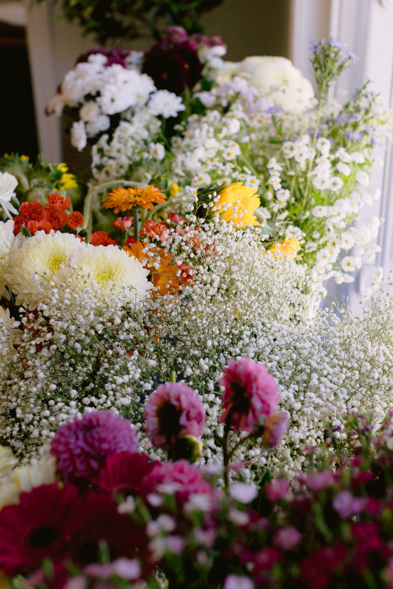 Colorful floral arrangement featuring baby's breath, chrysanthemums, zinnias, and mixed blooms in pink, white, yellow, and orange.