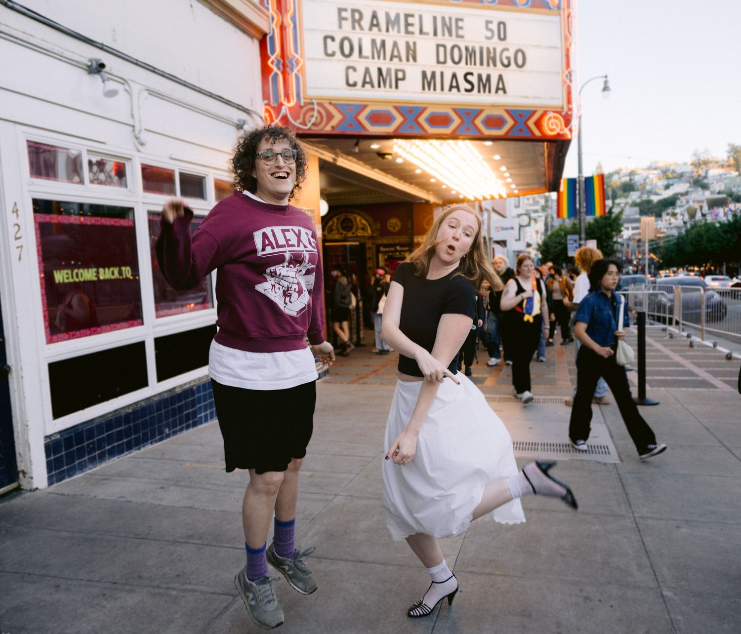 Two joyful people dance outside the Castro Theatre under the Frameline 50 marquee at dusk.