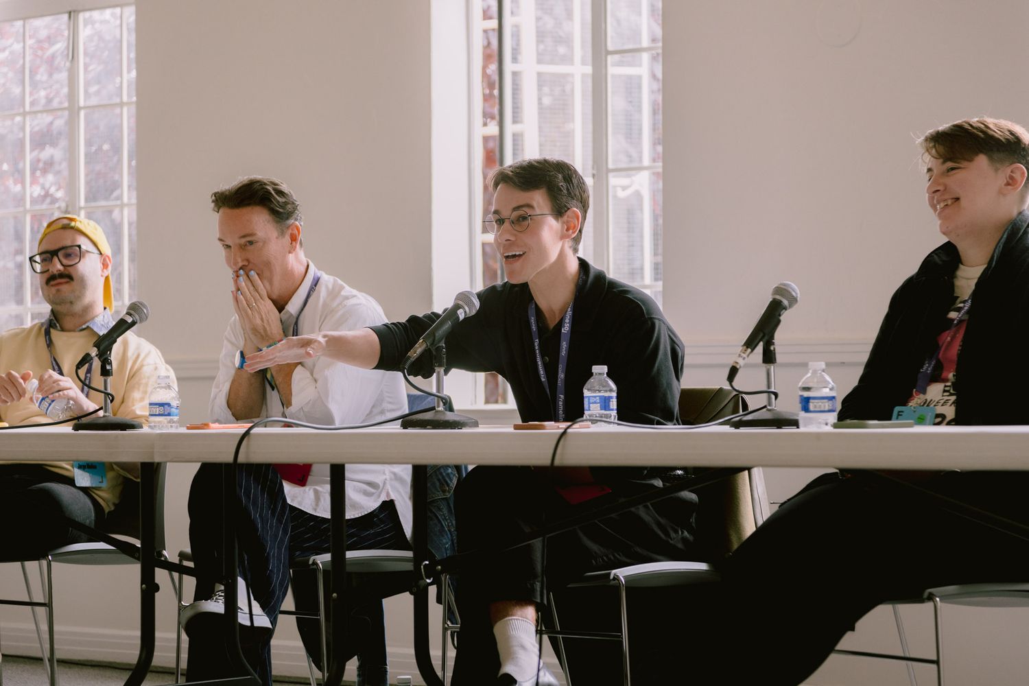 Four panelists seated at a table with microphones during an indoor discussion or conference.
