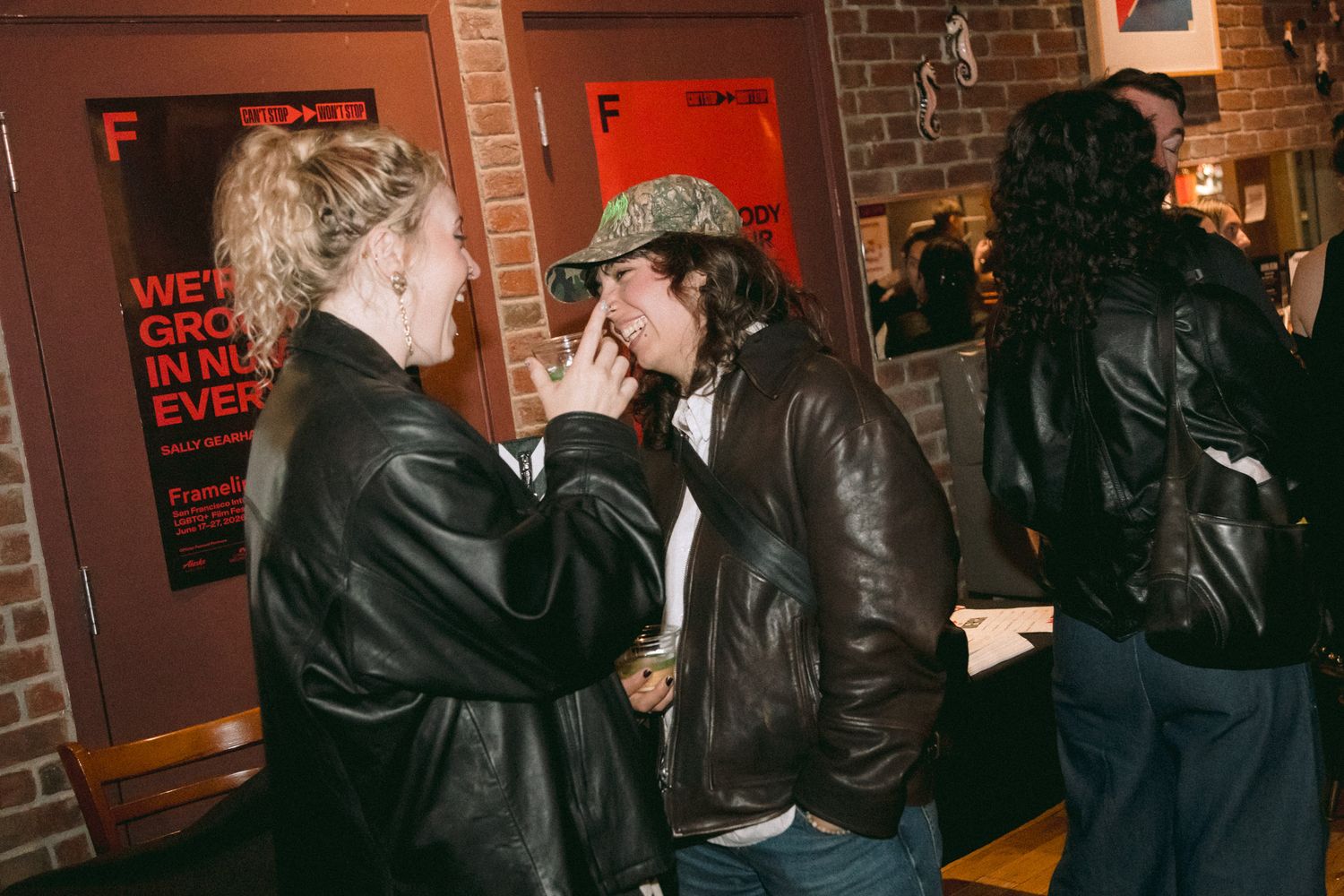 Two people in leather jackets having an intimate conversation outside a Frameline film festival venue.