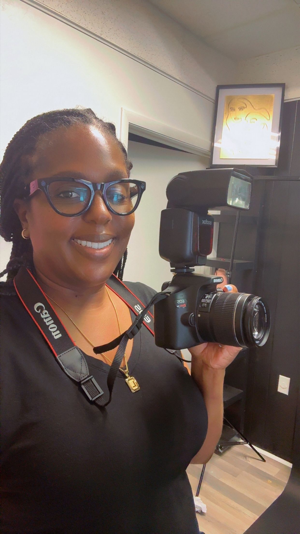 Smiling woman holding Canon DSLR camera with flash in a photography studio.