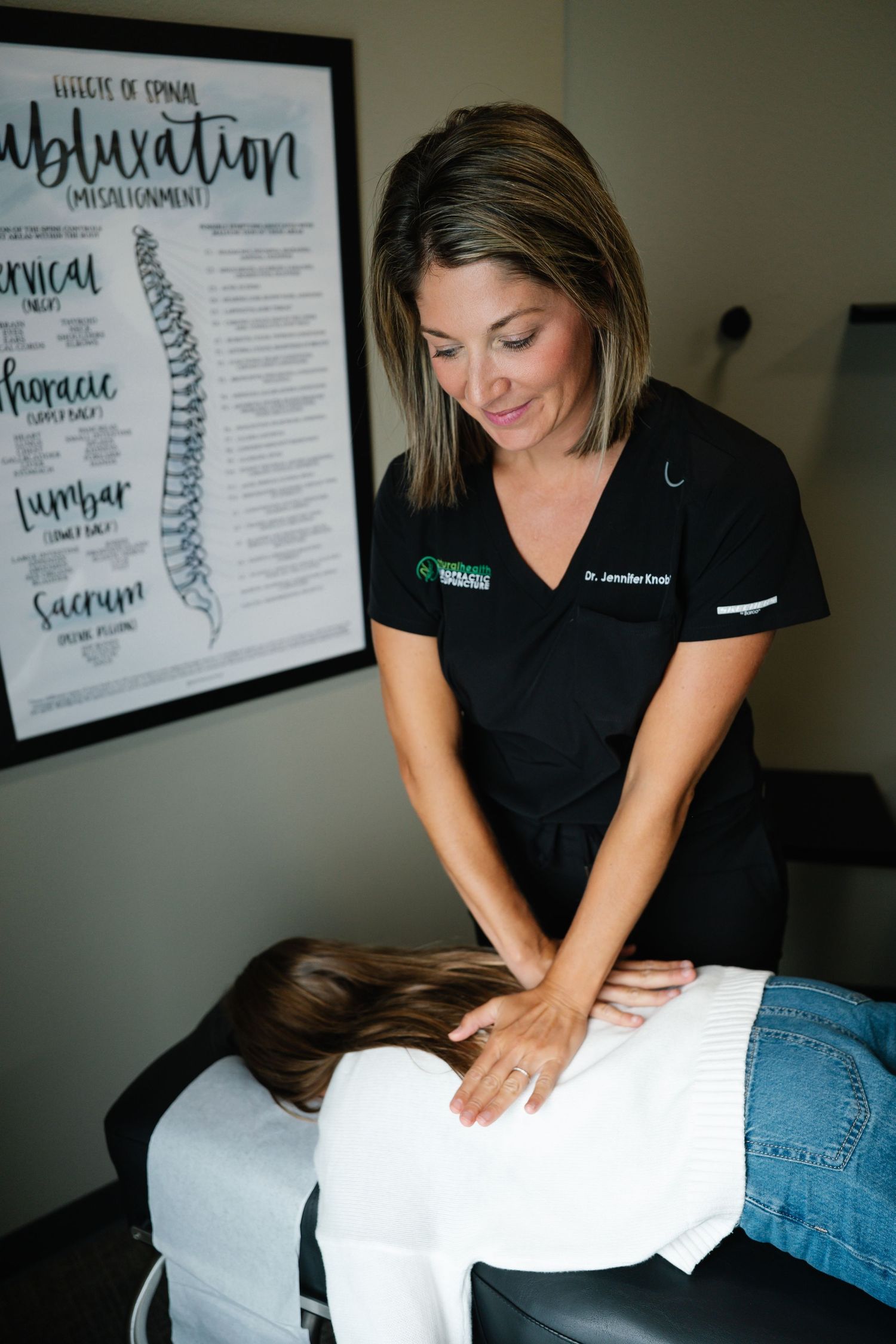 Chiropractor Dr. Jennifer Knoll performing a spinal adjustment on a patient in a chiropractic office.