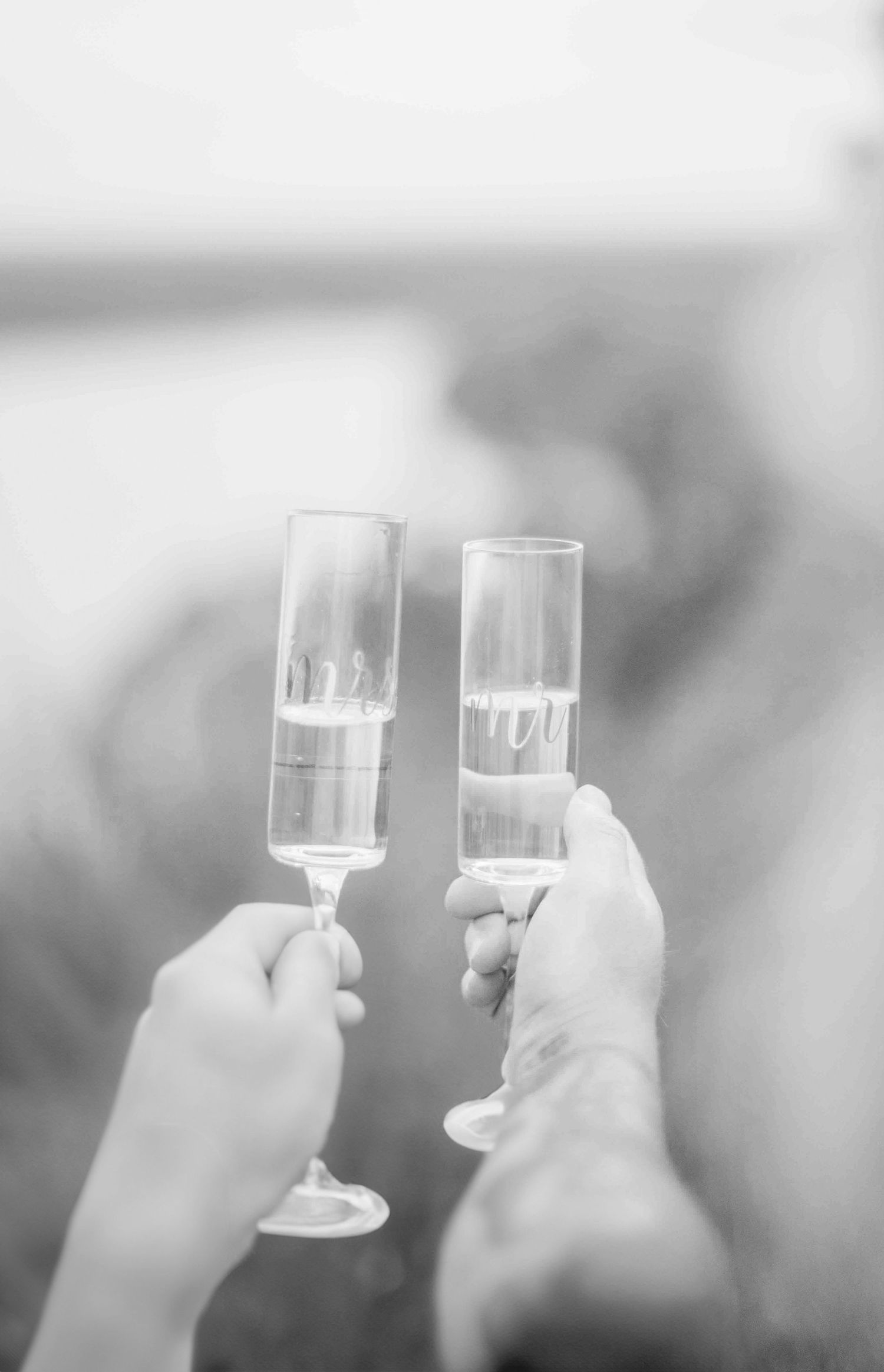Black and white photo of couple toasting with champagne flutes in celebration of their engagement.