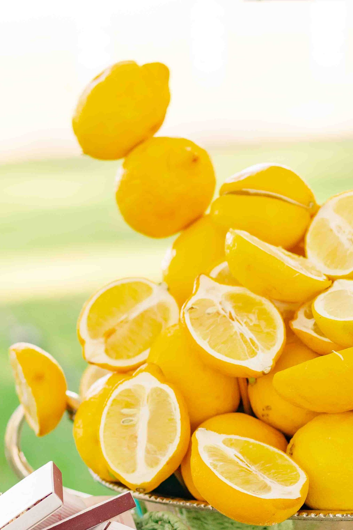 Decorative arrangement of fresh whole and halved yellow lemons on display outdoors.