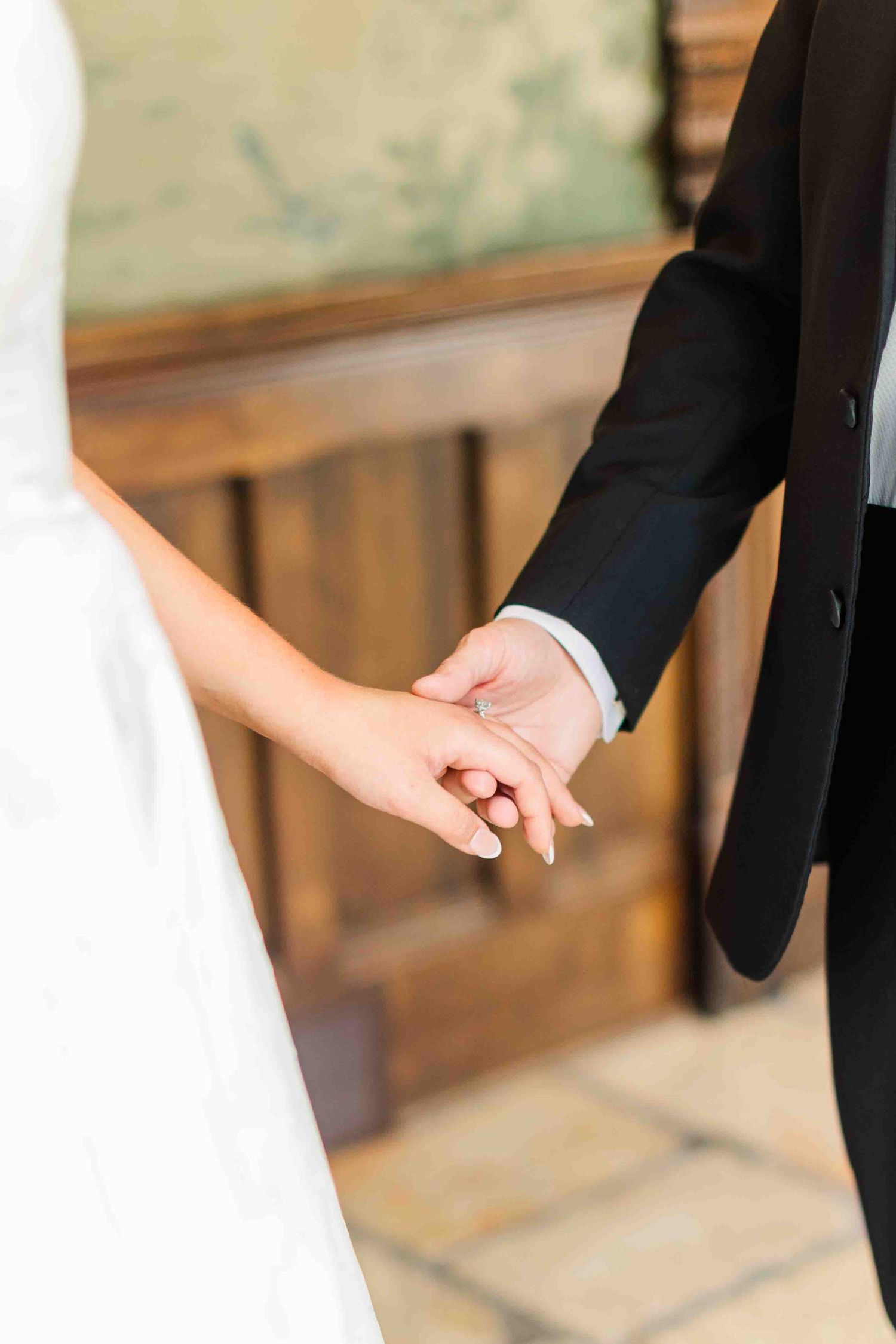 Close-up of bride and groom holding hands at wedding ceremony.