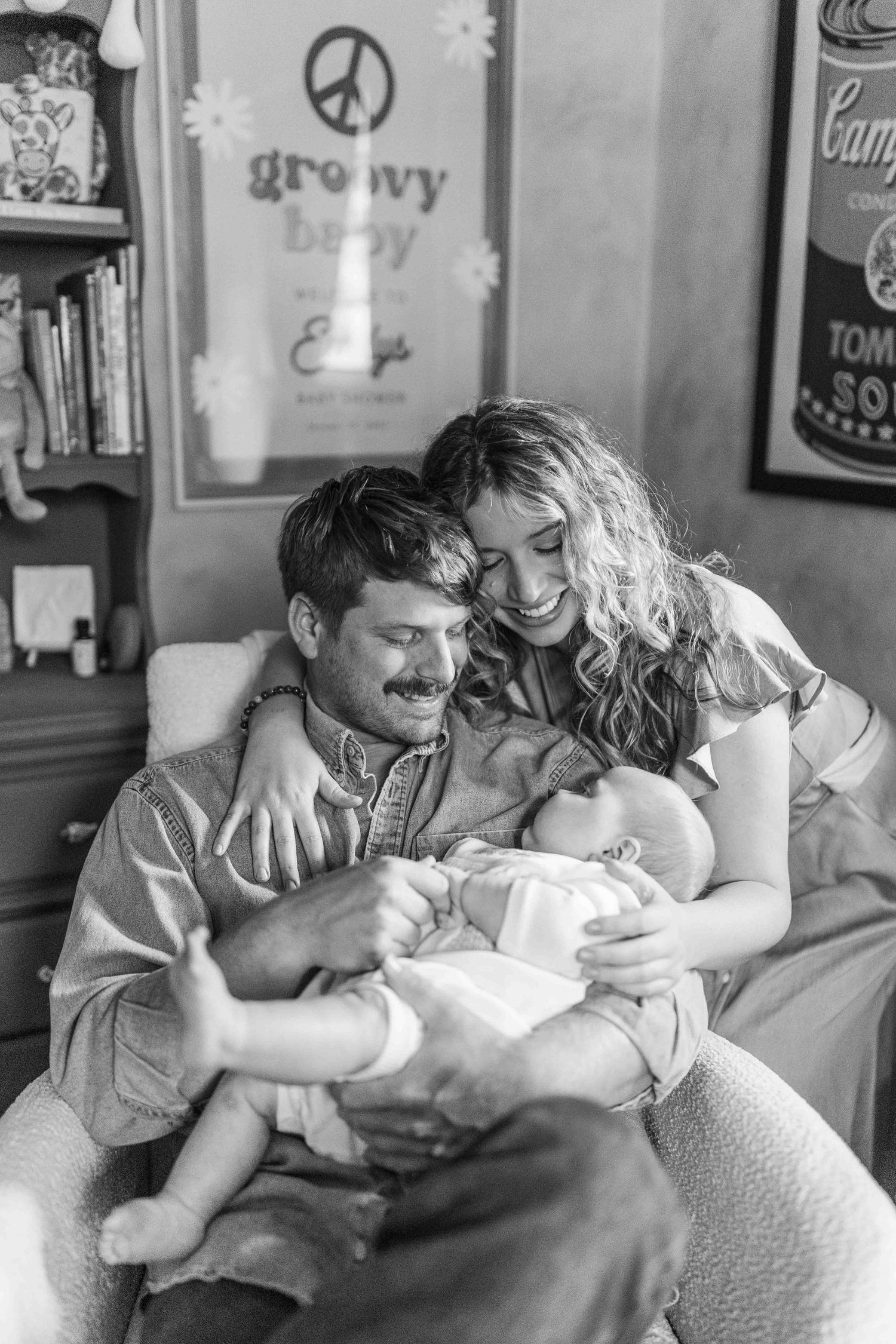 Happy couple smiling and bonding with their newborn baby in a groovy decorated nursery room.
