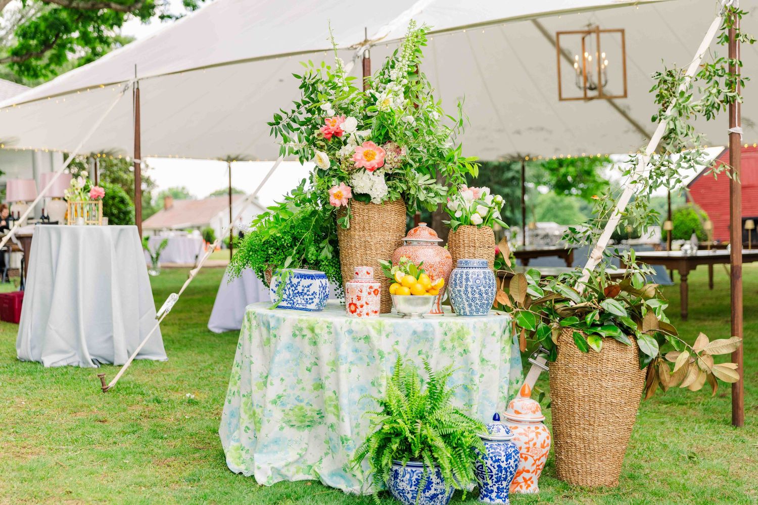 Elegant outdoor wedding reception table display with floral arrangements under tent.