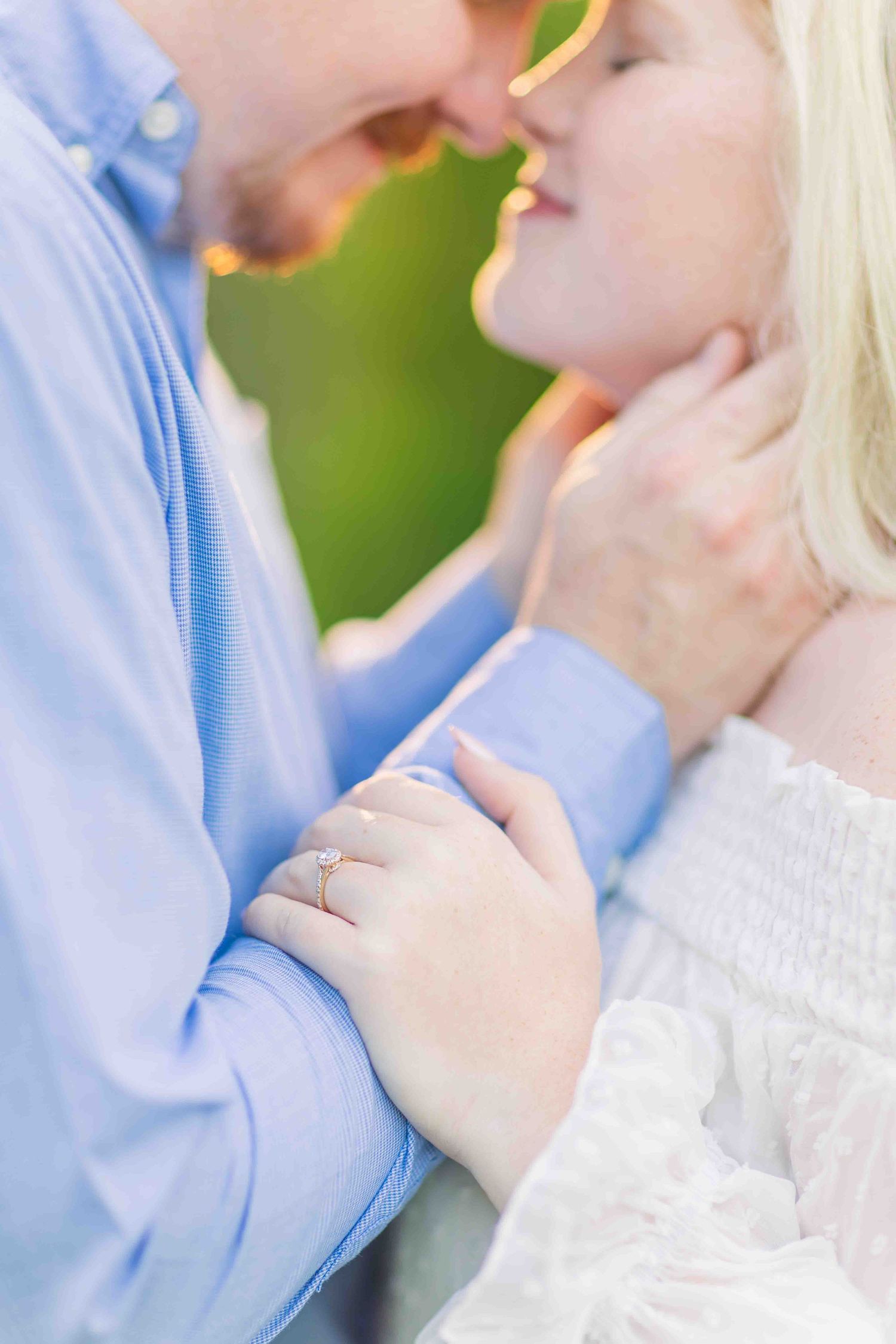 Close-up of couple nearly kissing with focus on woman's delicate diamond ring on her hand.