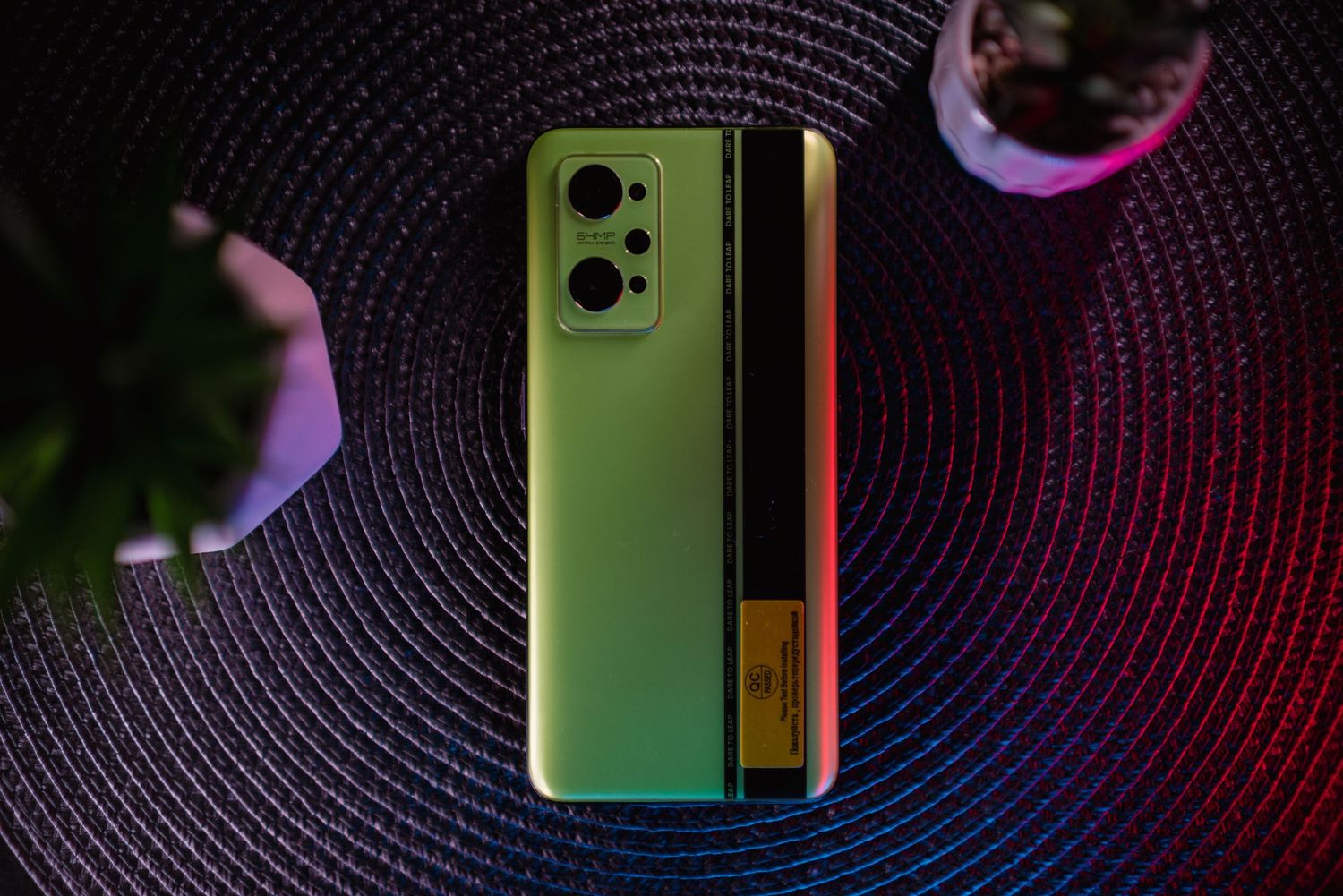 Realme GT Neo 2 5G smartphone in green gradient color displayed on dark woven surface.