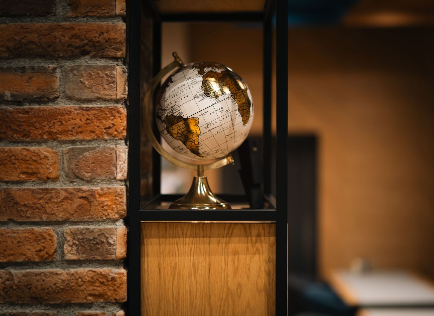 Decorative gold and white globe on wooden shelf beside exposed brick wall in cafe interior.