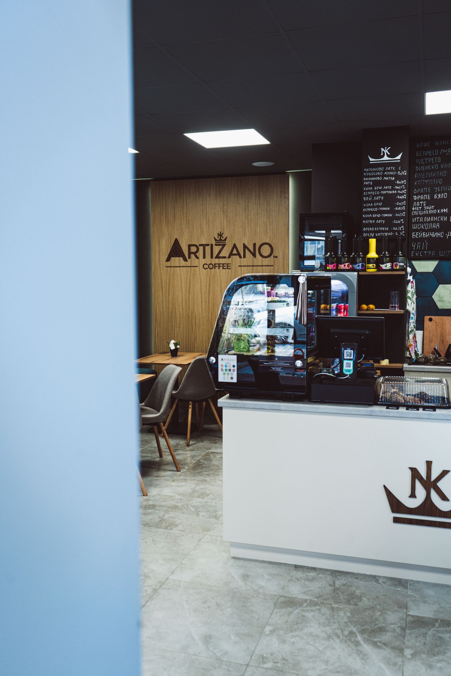 Artizano Coffee shop entrance view showing espresso bar counter, display case, and seating area.