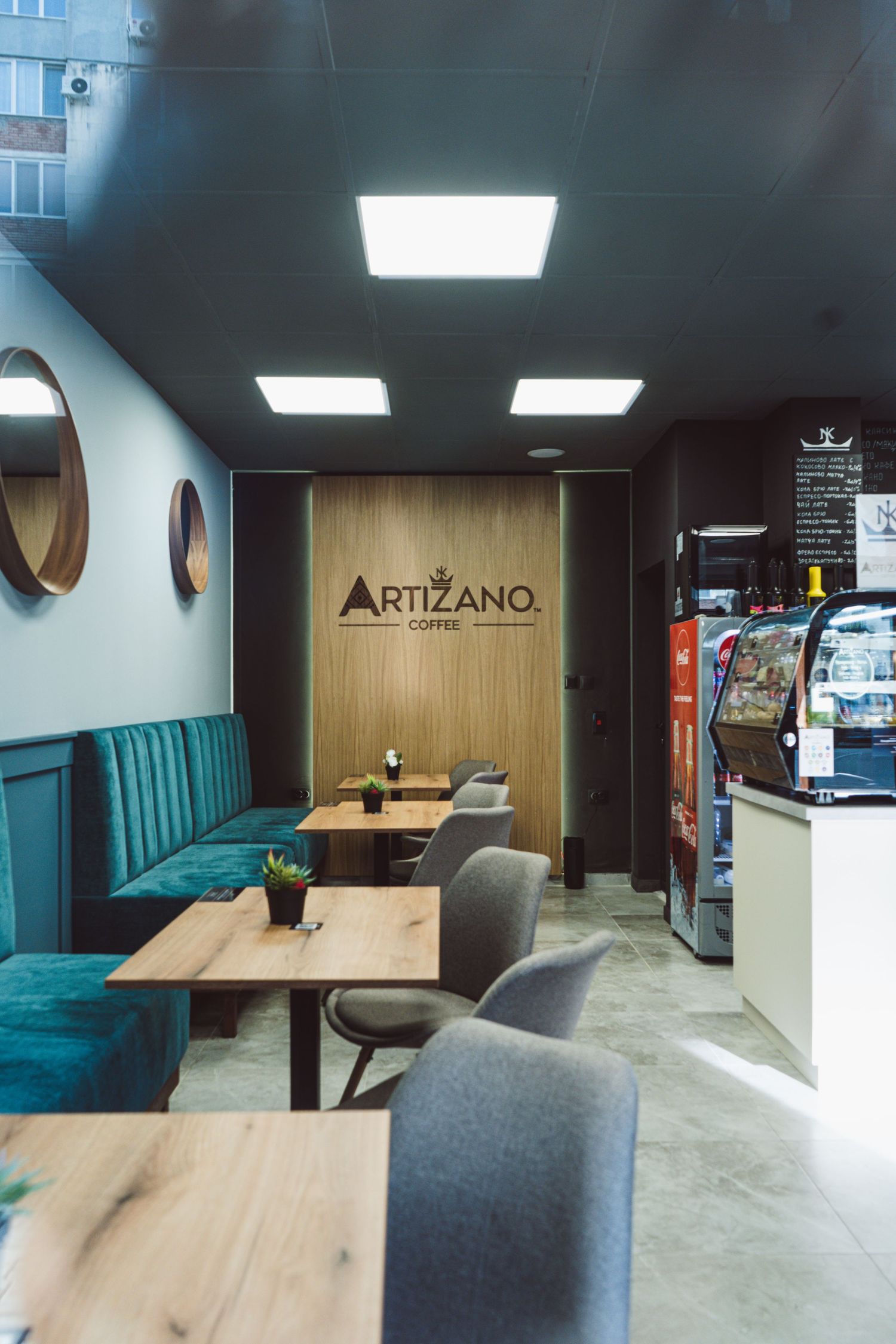 Artizano Coffee cafe interior with teal velvet booth seating, wooden tables, and service counter.