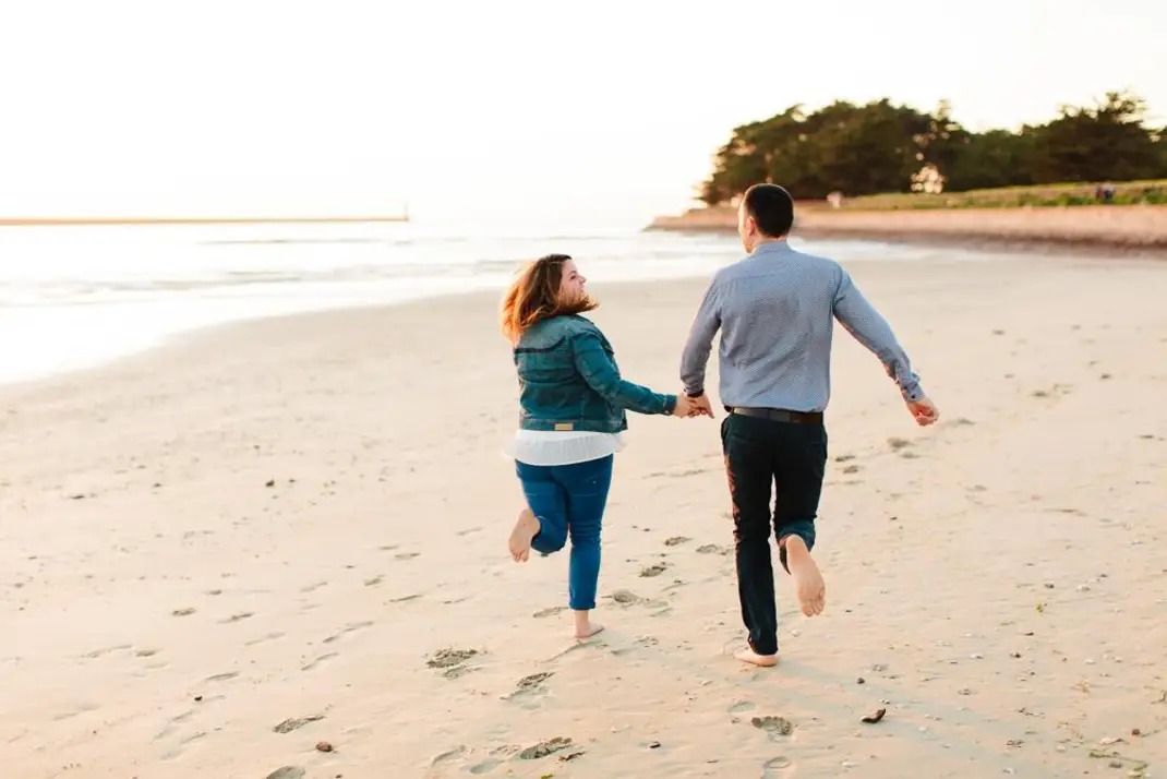 séance de couple au bord de la mer, deux amoureux courent sur la plage