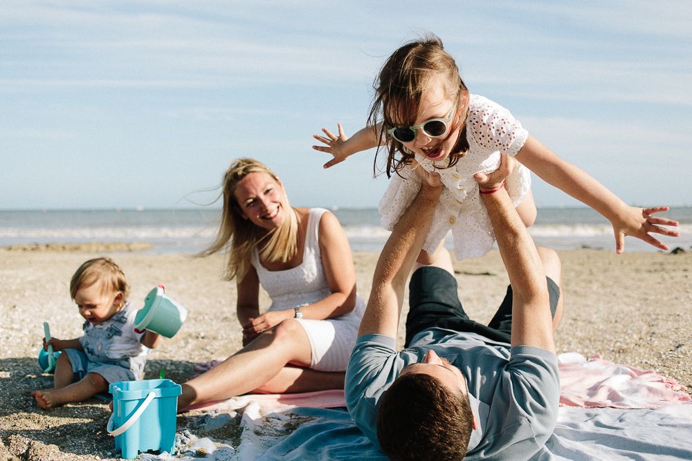 famille qui partage un moment de jeu à la plage lors d'une séance photo avec une photographe d'Angers