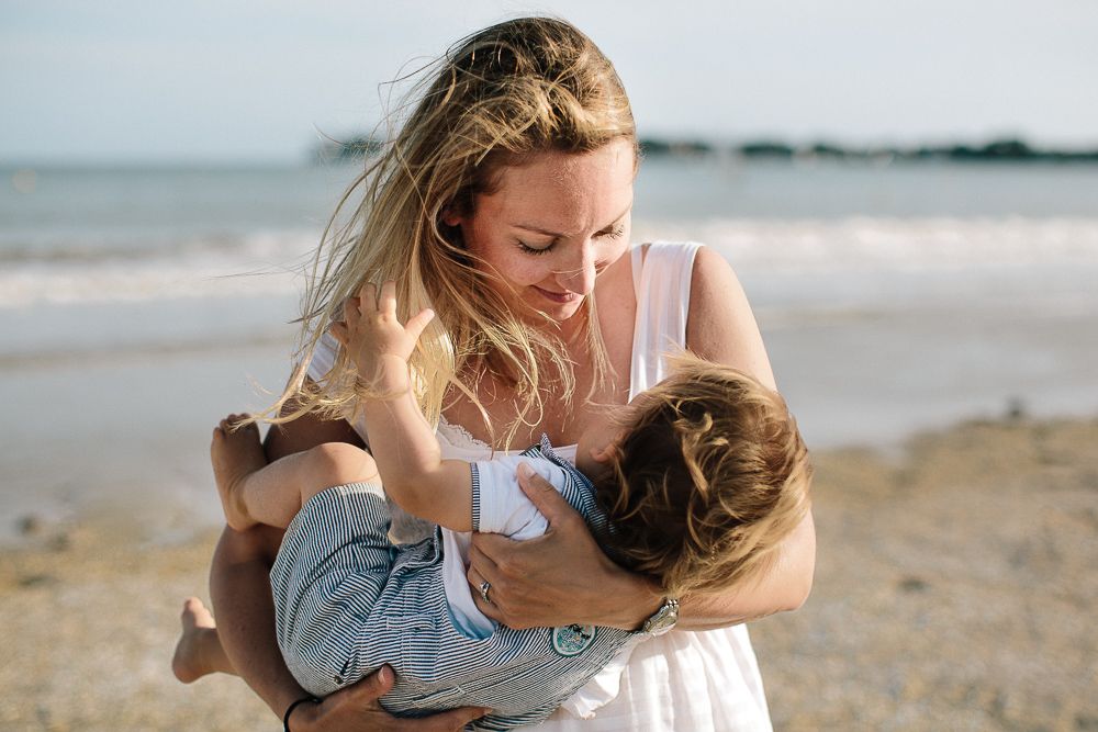 maman qui porte son enfant au bord de la mer lors d'une séance photo avec une photographe d'Angers