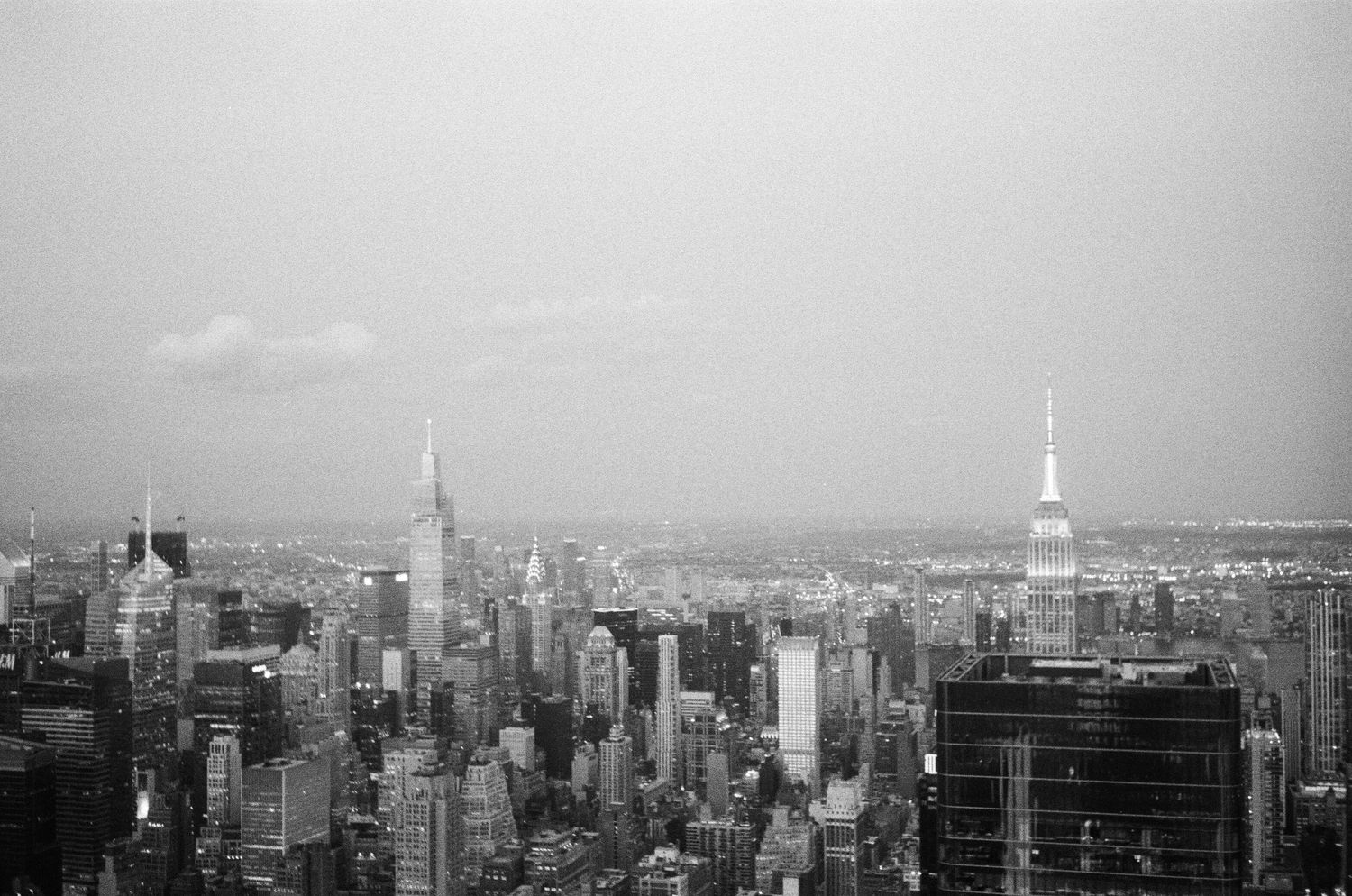 The expansive Manhattan skyline appears in a grayscale, high-angle aerial view.
