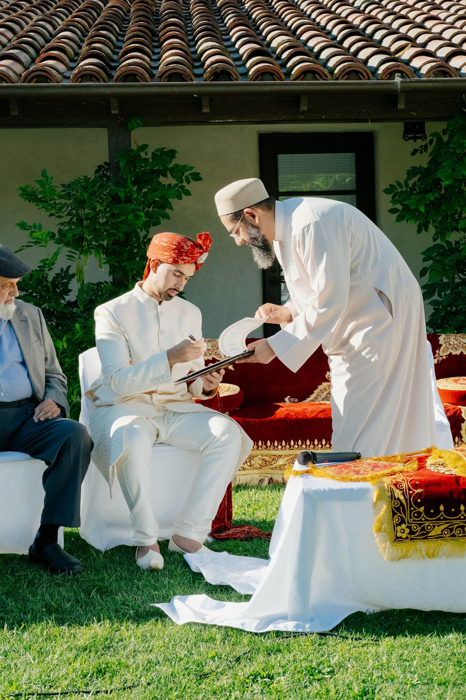 A religious official officiates a document signing ceremony for a groom in a turban.