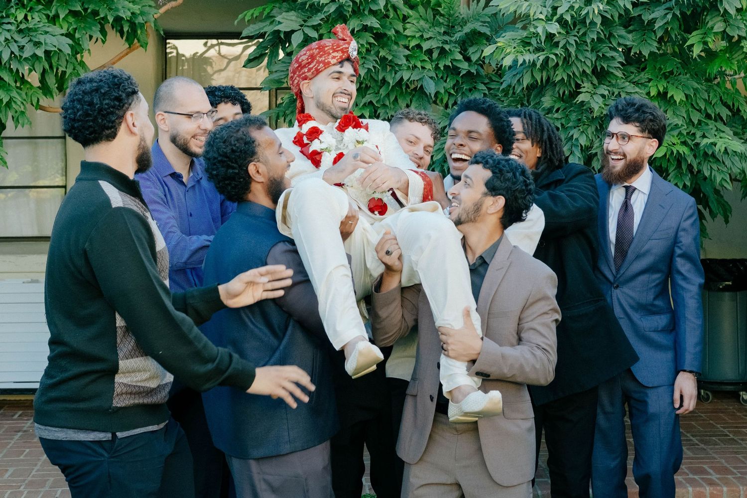 Friends lift the groom into the air during a joyous and celebratory moment at the wedding.