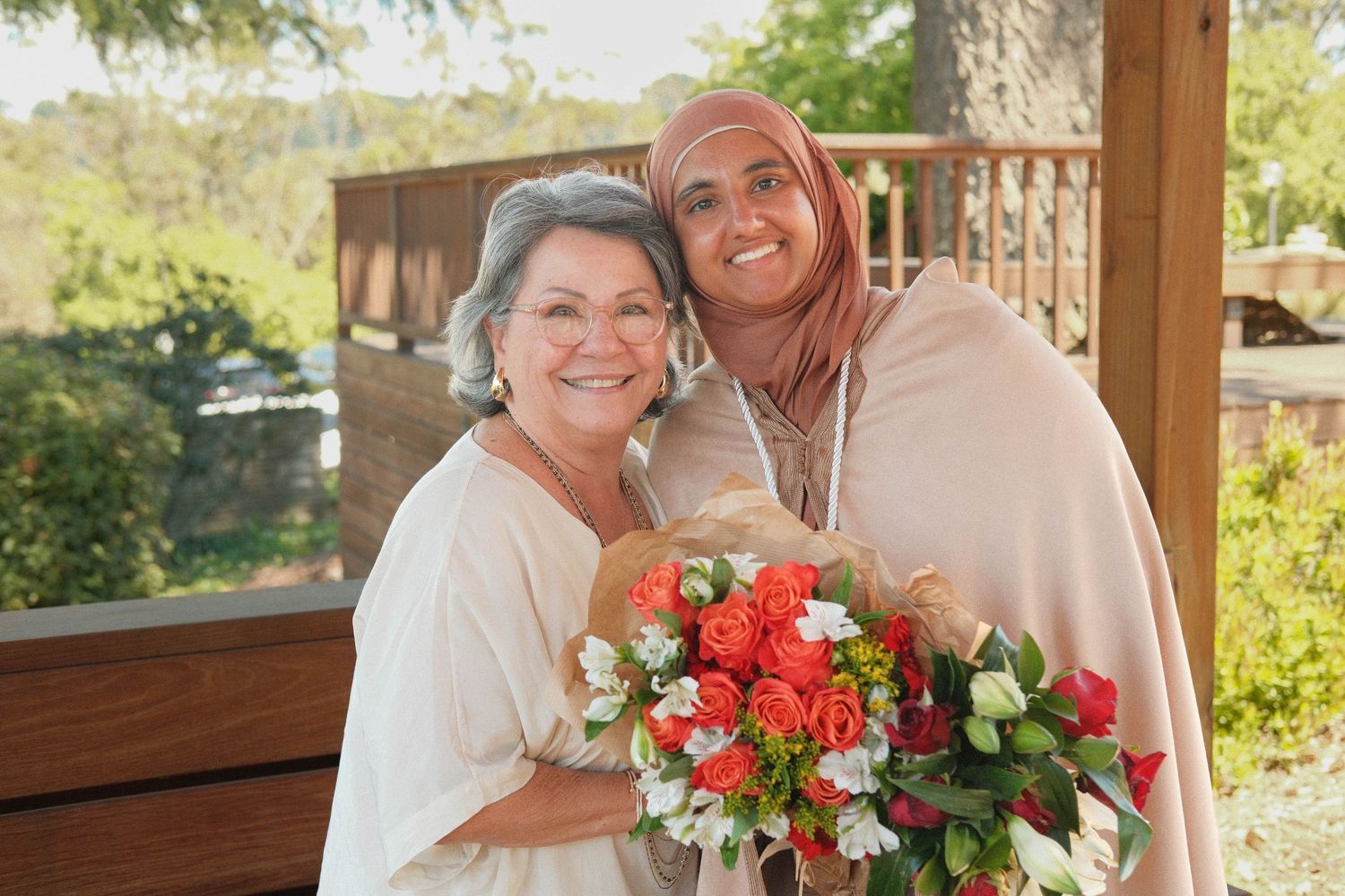 Portrait of a grandmother/granddaughter smiling with a bouqet.