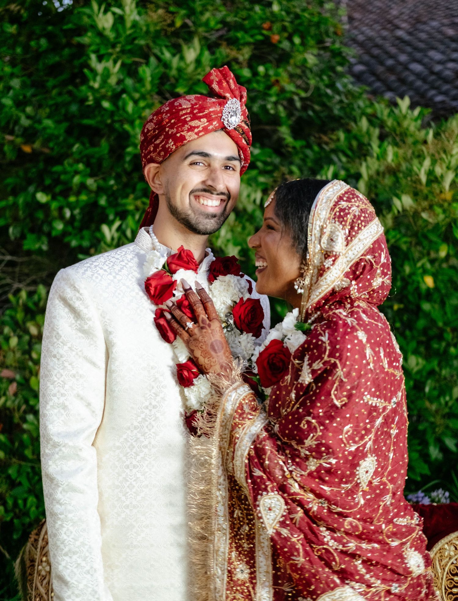 A bride and groom in traditional wedding attire share a joyous moment.
