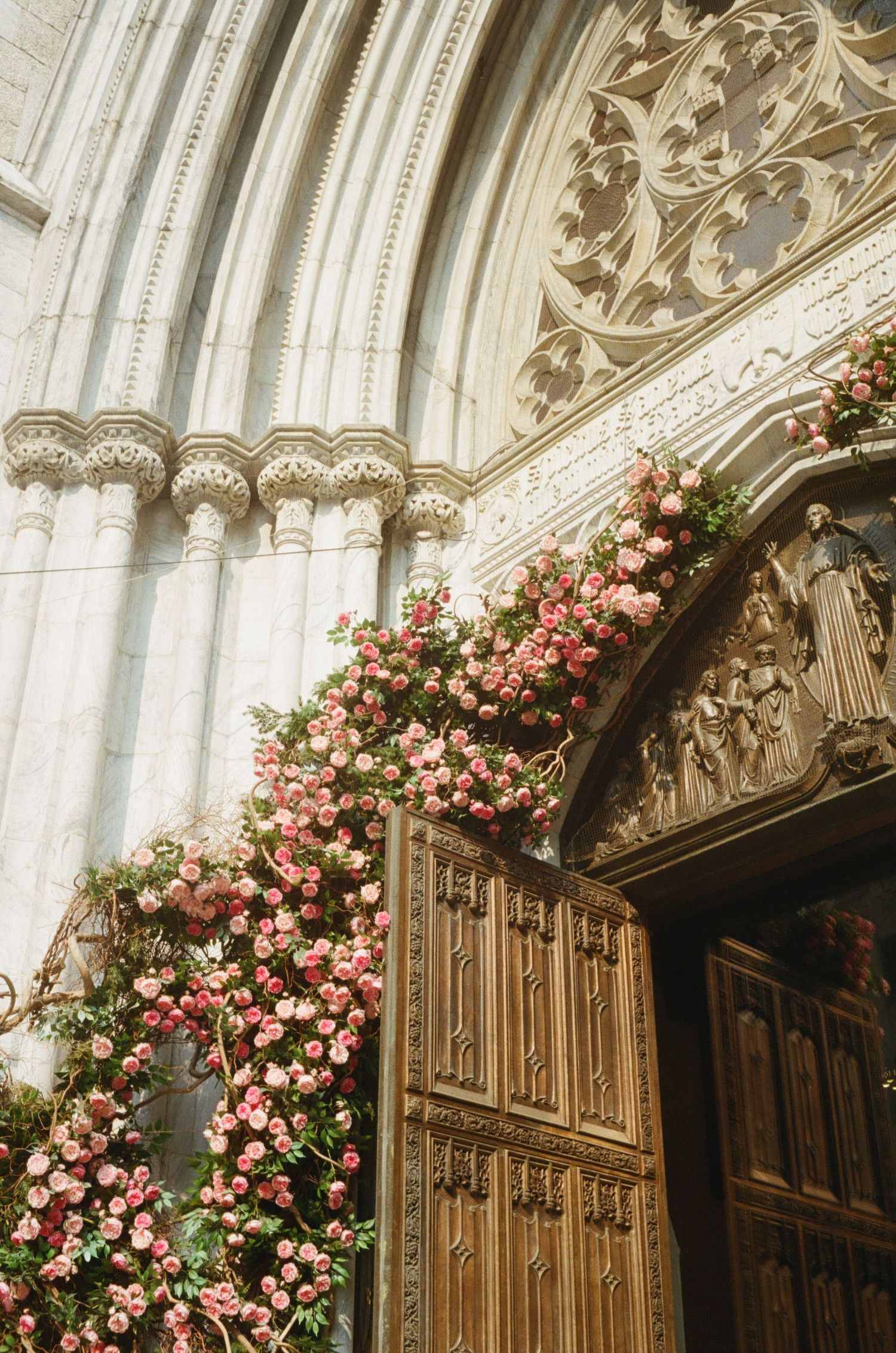 An ornate church doorway is decorated with beautiful, cascading pink roses.