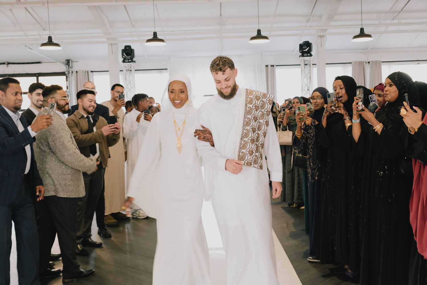 The bride and groom walk hand-in-hand down the aisle, cheered on by their wedding guests.