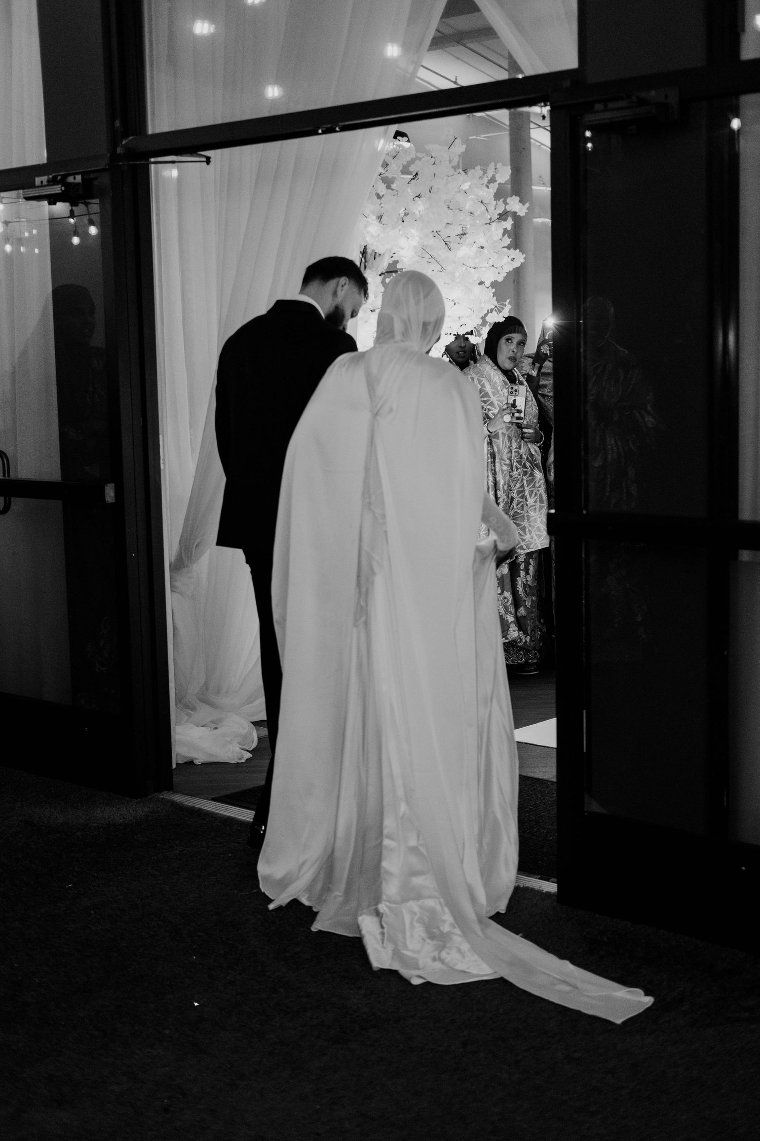 A bride in an elegant gown walks through a doorway with her groom.