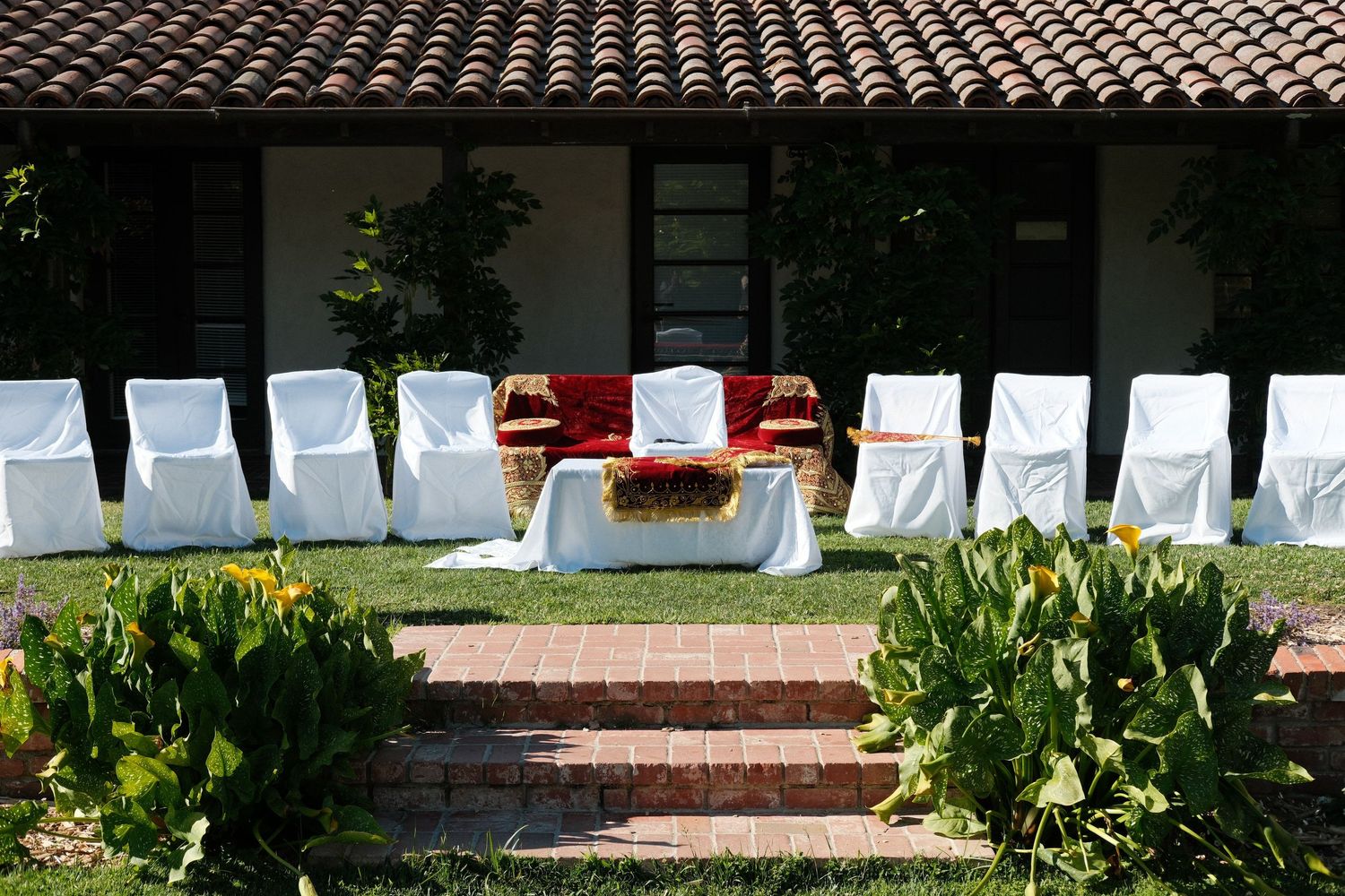 White chairs are arranged for an outdoor ceremony on grass.