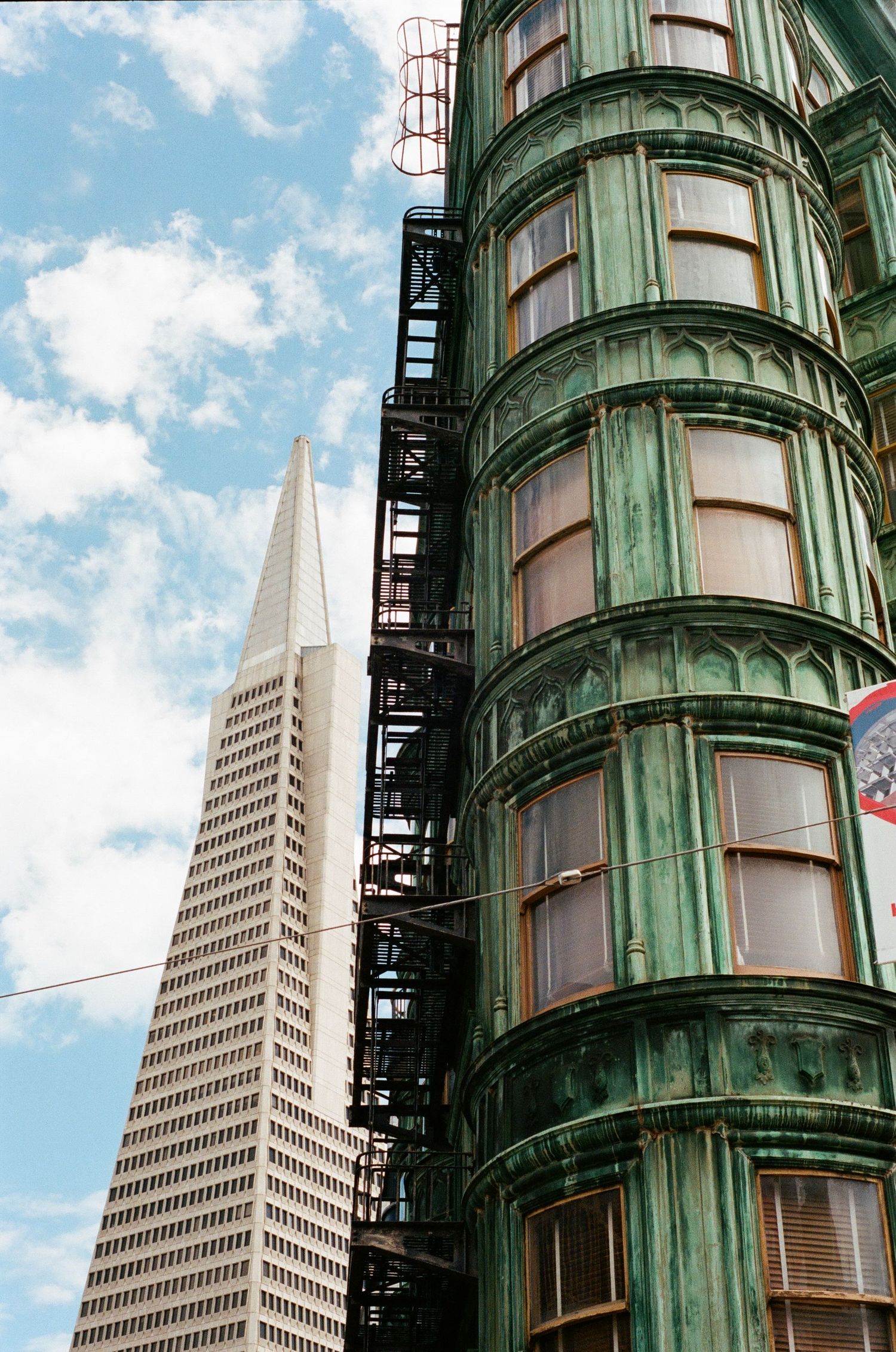 The Transamerica Pyramid towers behind a historic green building.