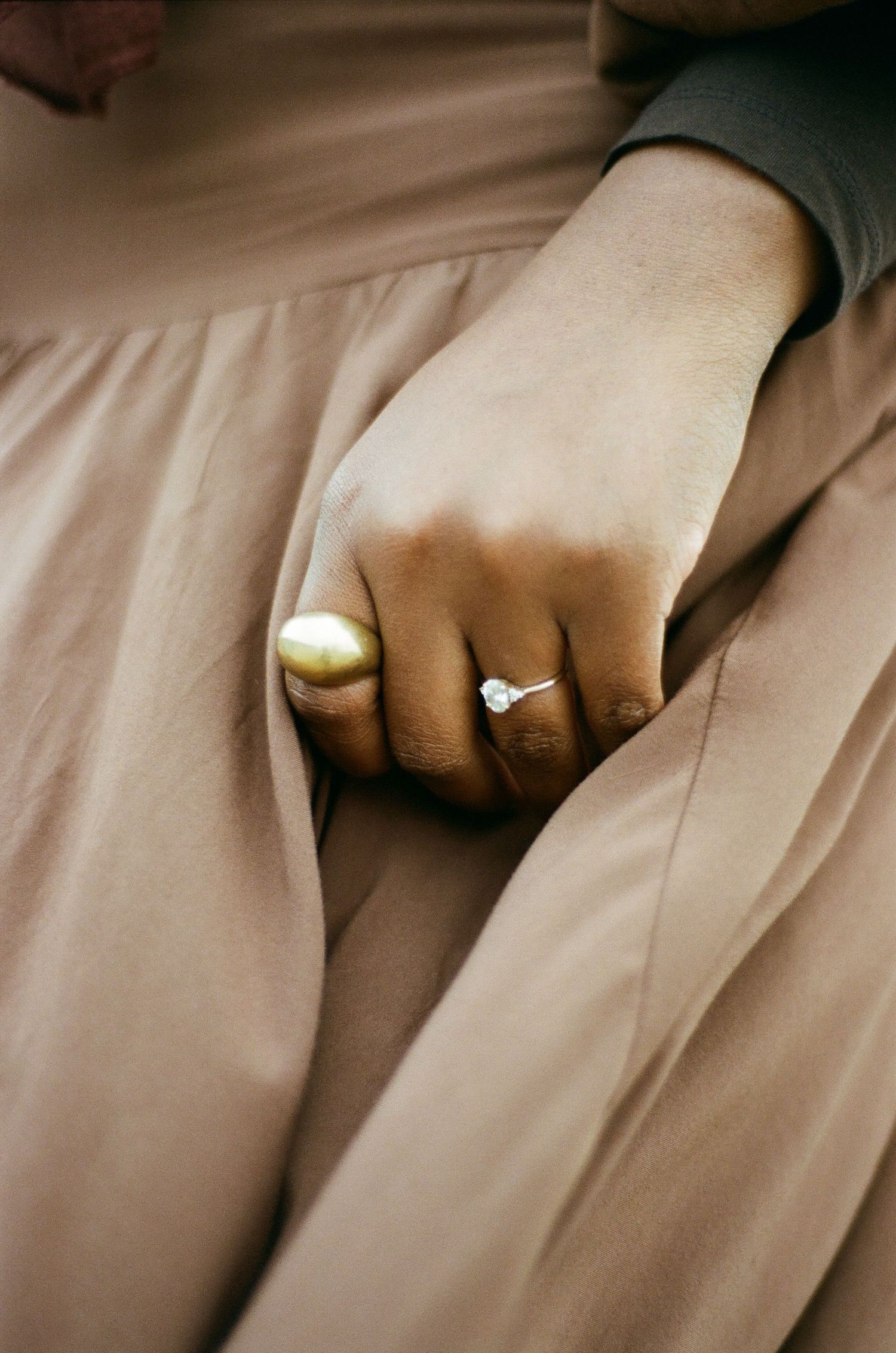 Film photo of a hand with two rings and a brown dress