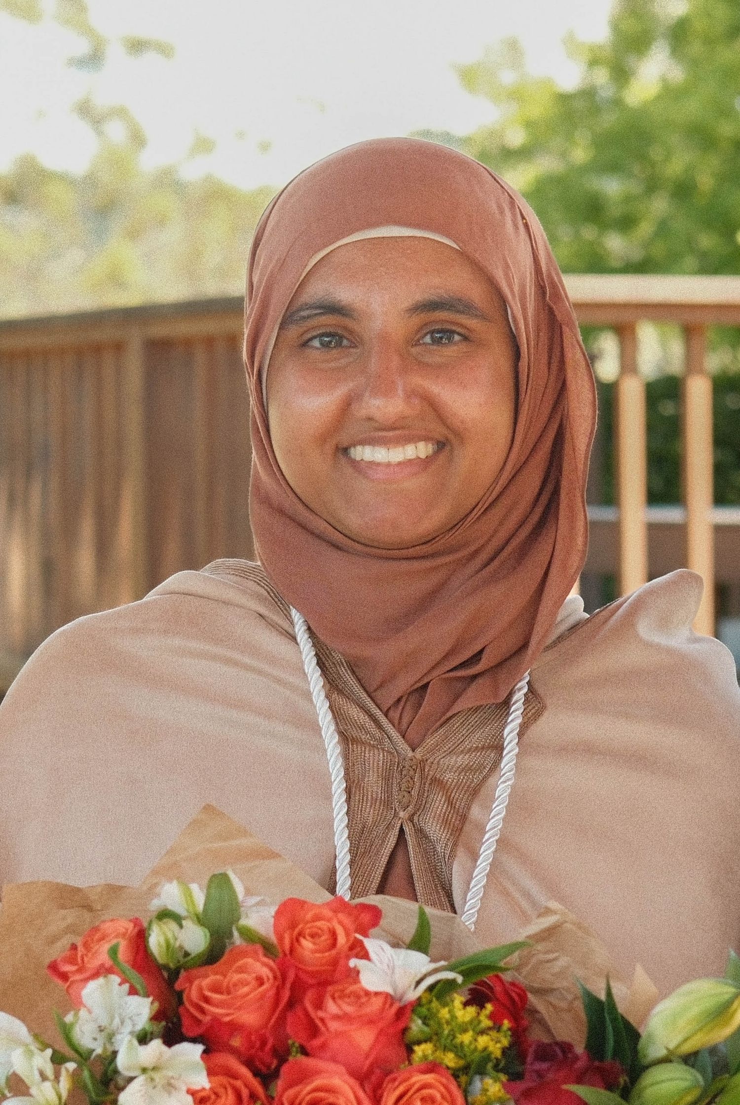 Portrait of a hijabi smiling with a bouqet.