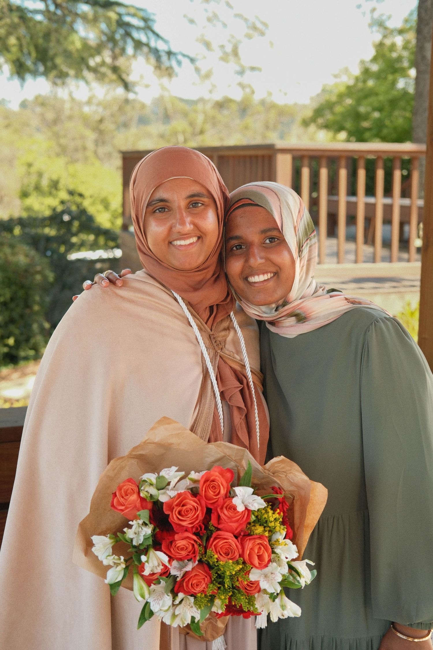 Portrait of 2 hijabis smiling with a bouqet.