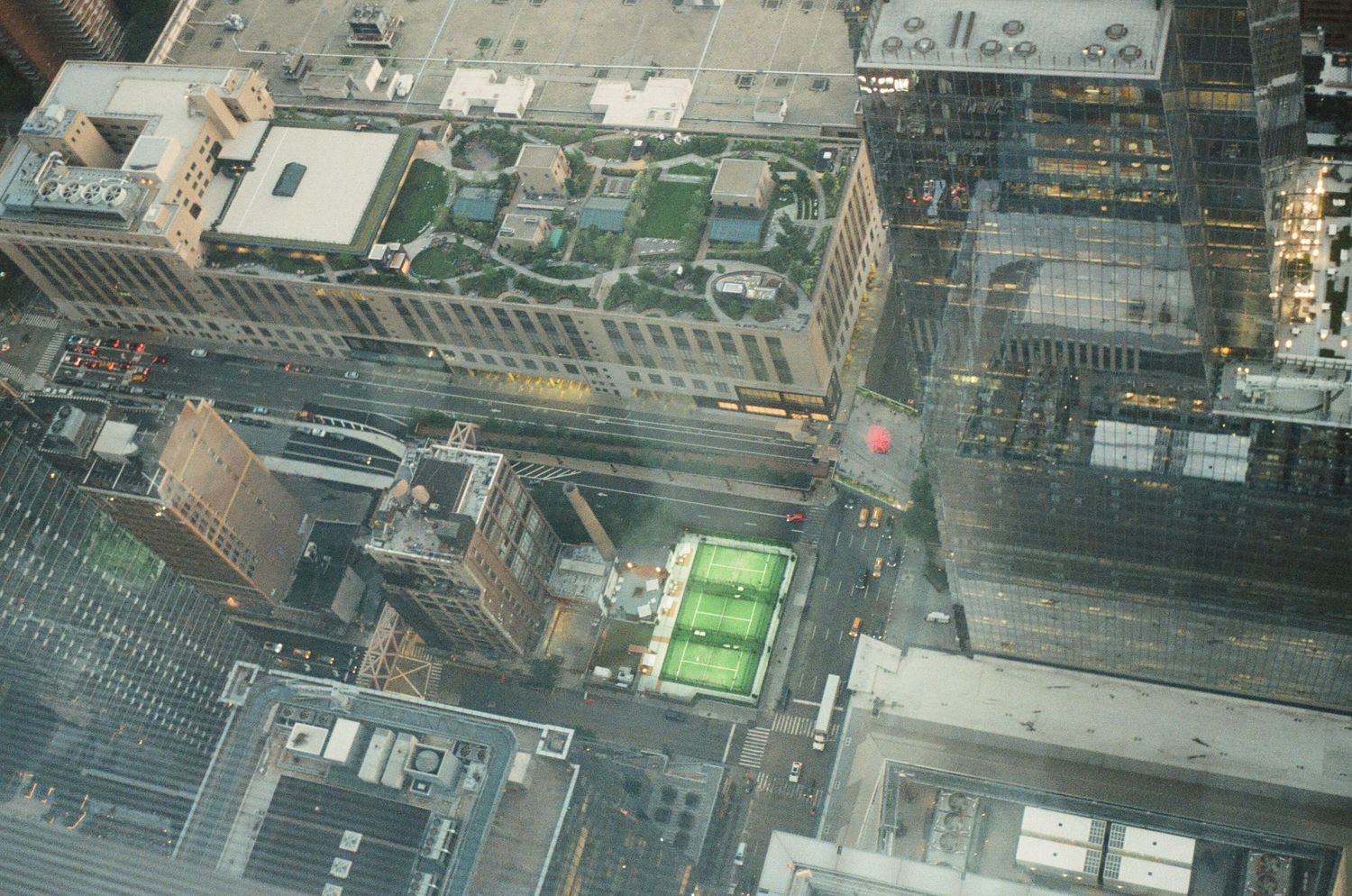 An aerial view shows city buildings, a rooftop garden, and courts.