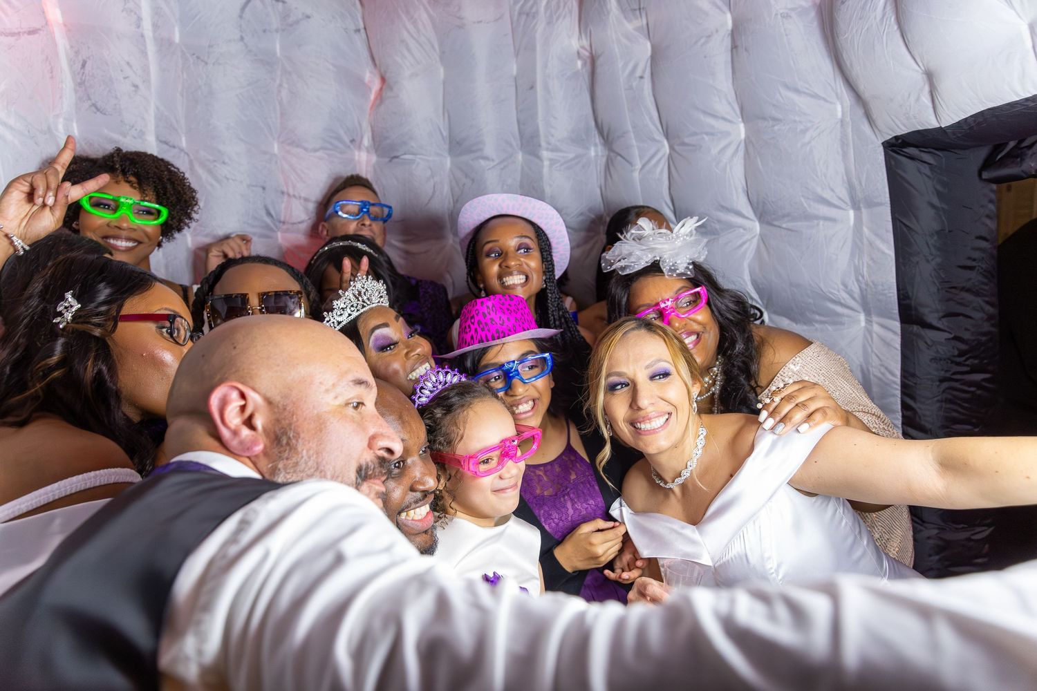 Event guests making playful expressions together in a photo booth.Event guests posing together in a photo booth with colorful novelty glasse