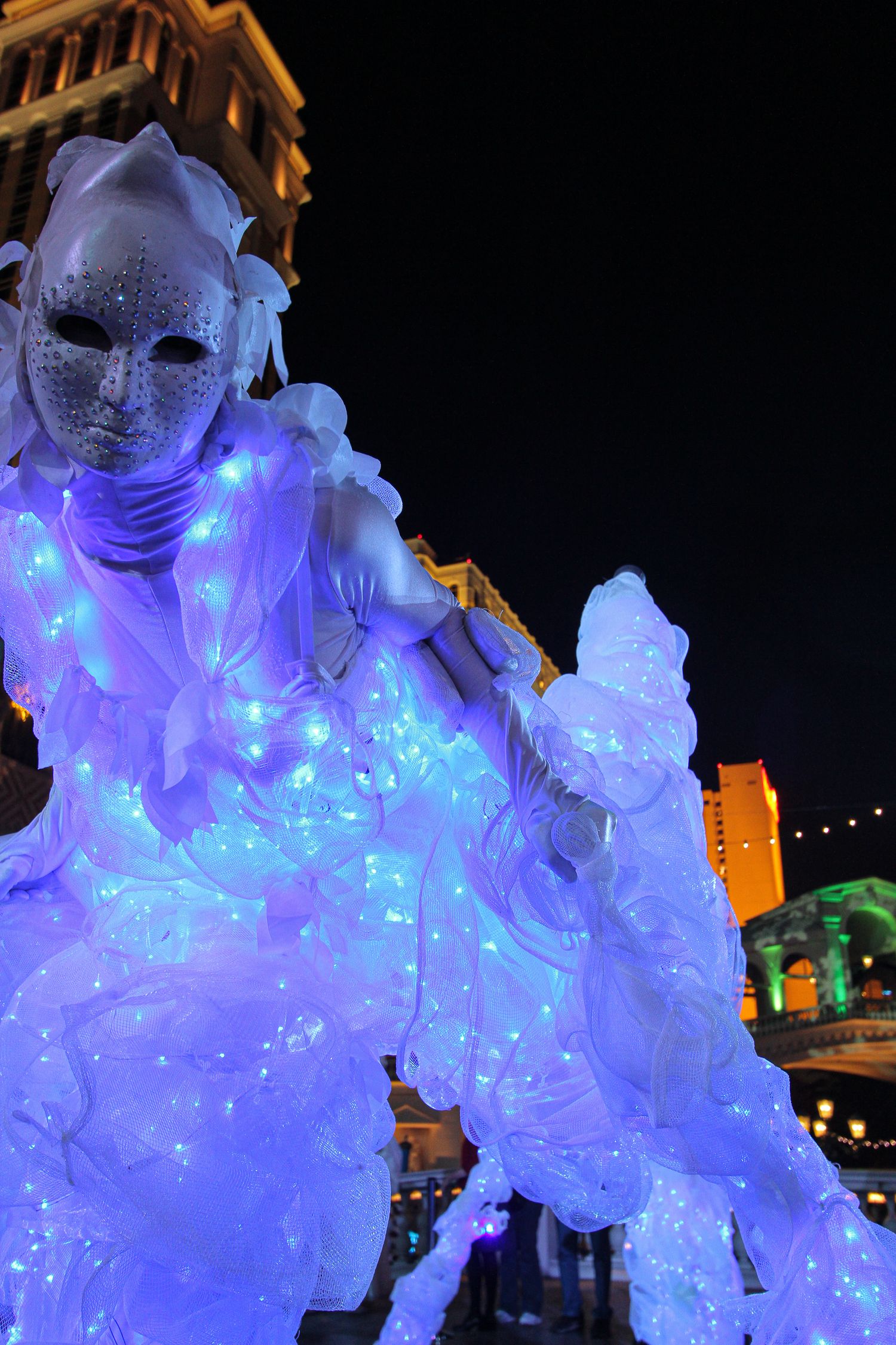 Illuminated costumed performer appearing at an evening event.