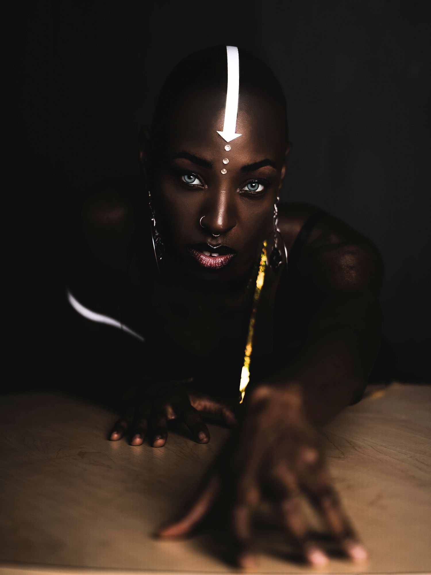 Dramatic low-key portrait of a woman reaching toward the camera.