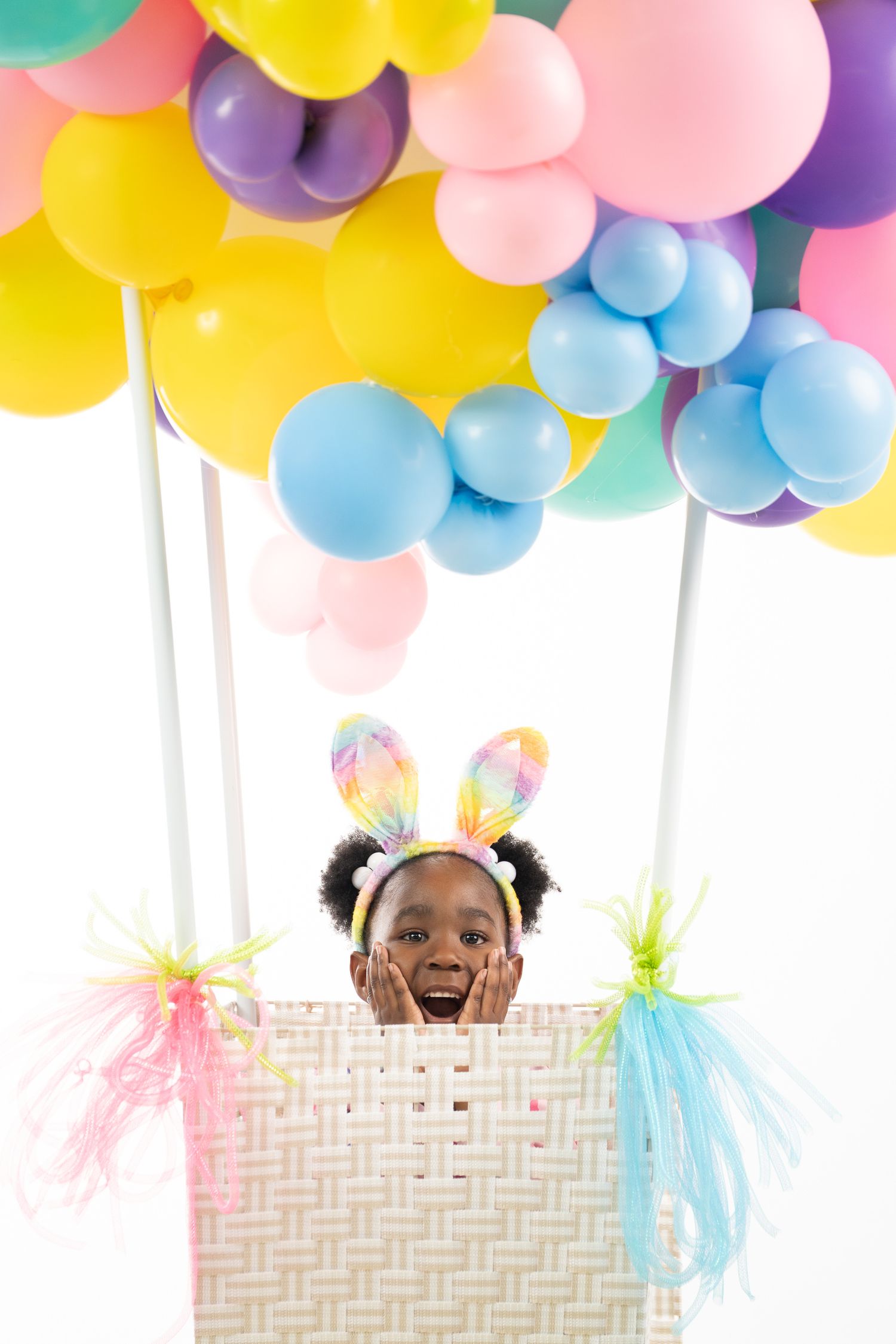 Colorful birthday branding portrait with a woman appearing from a gift box beneath balloons.
