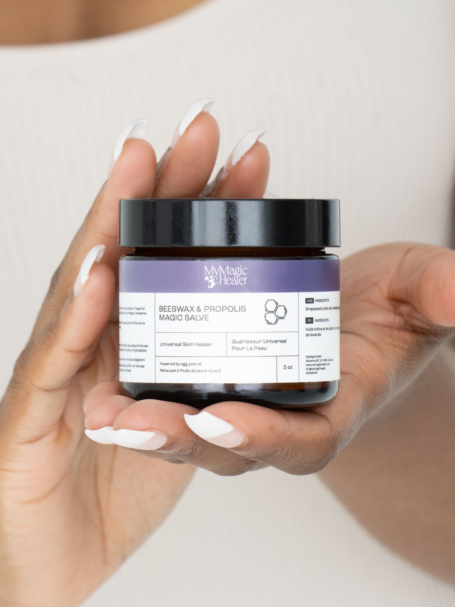 Hands presenting a skincare jar against a clean neutral background.