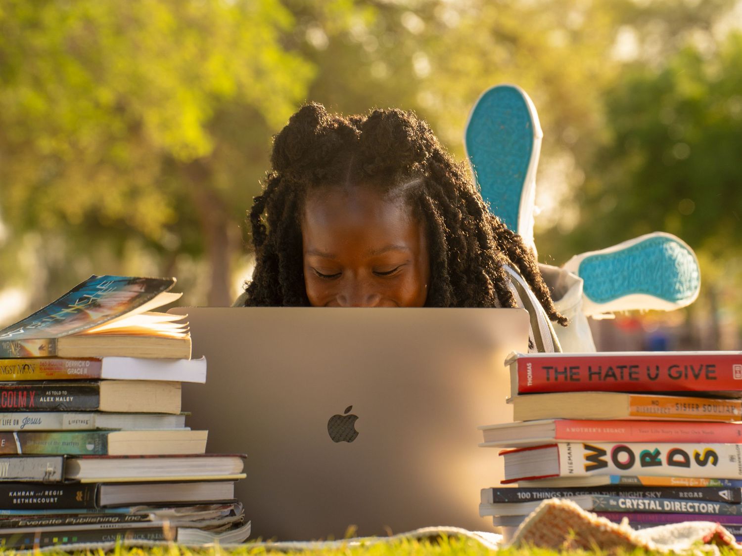 Entrepreneur working on a laptop outdoors with books and creative tools.