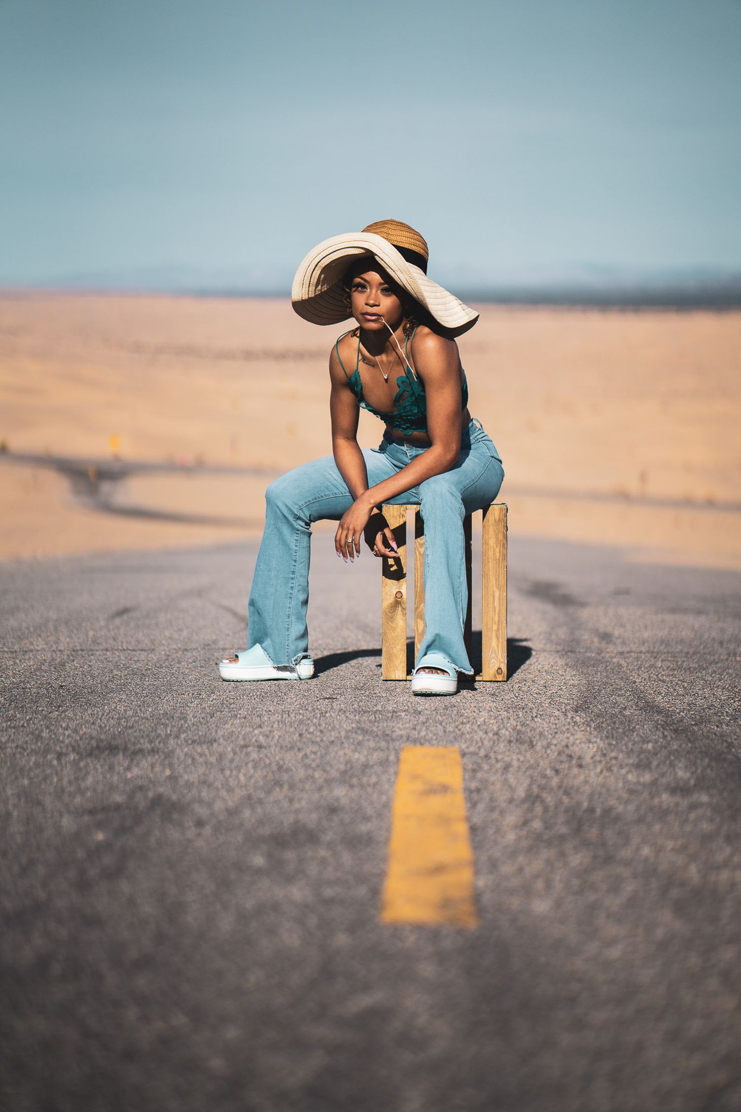 Fashion portrait of a woman crouching on an open desert road.