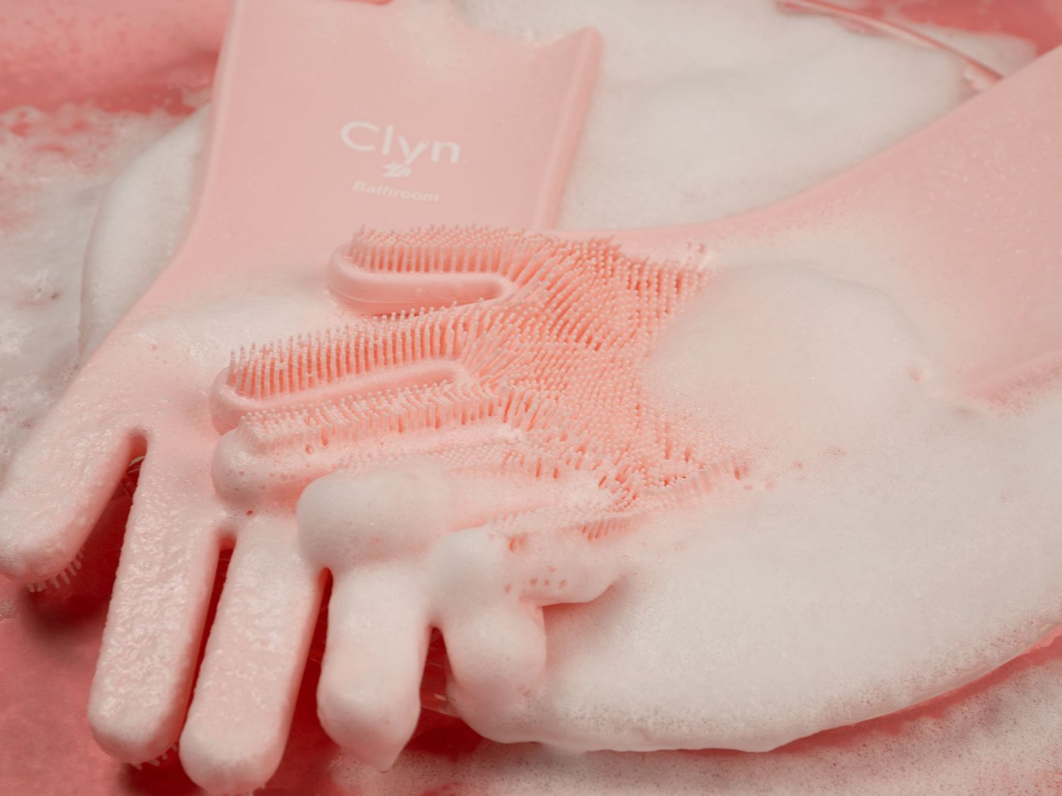 Hands presenting a pink hair-care styling tool against a soft blush background.