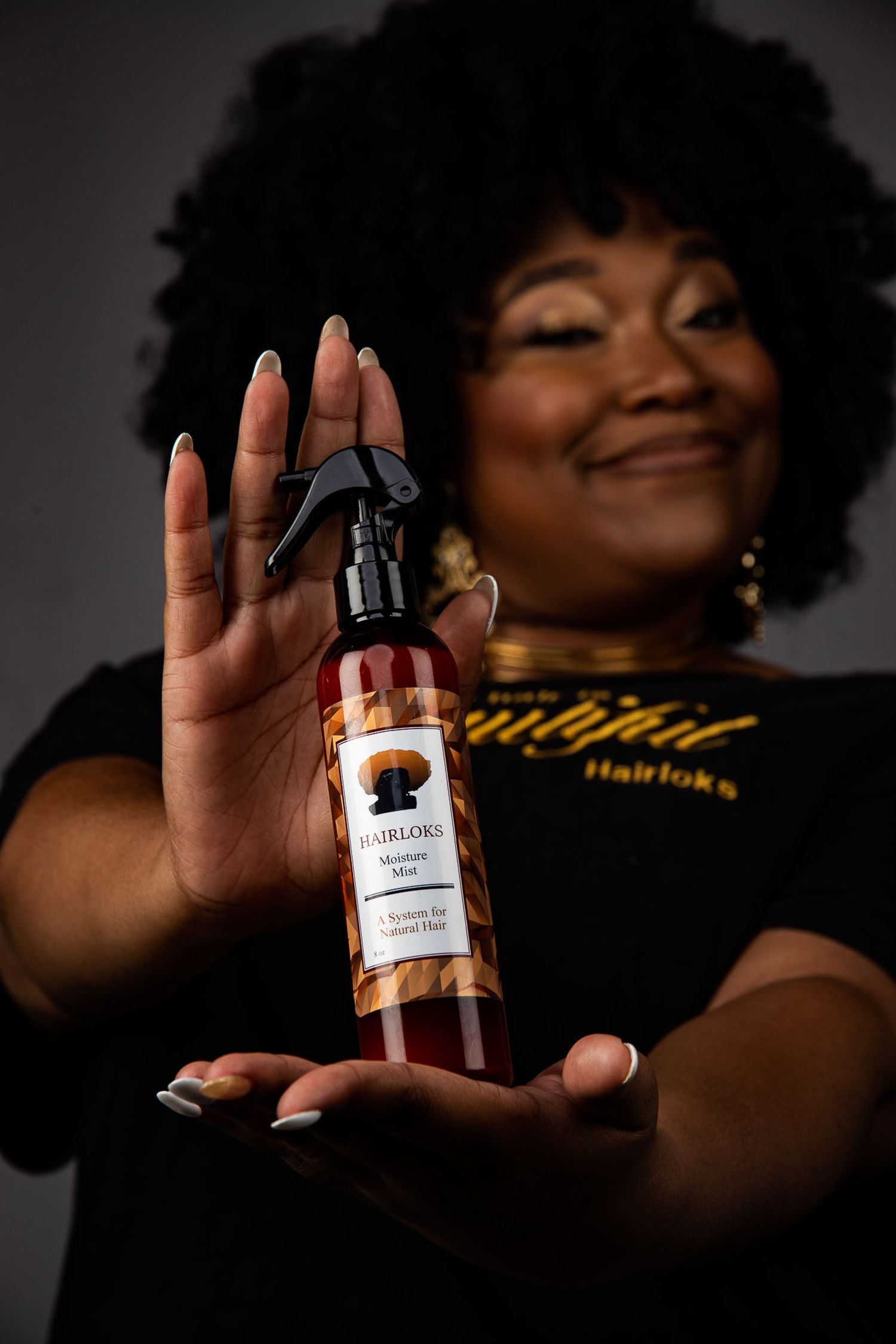 Business owner presenting a bottled product against a dramatic black background.