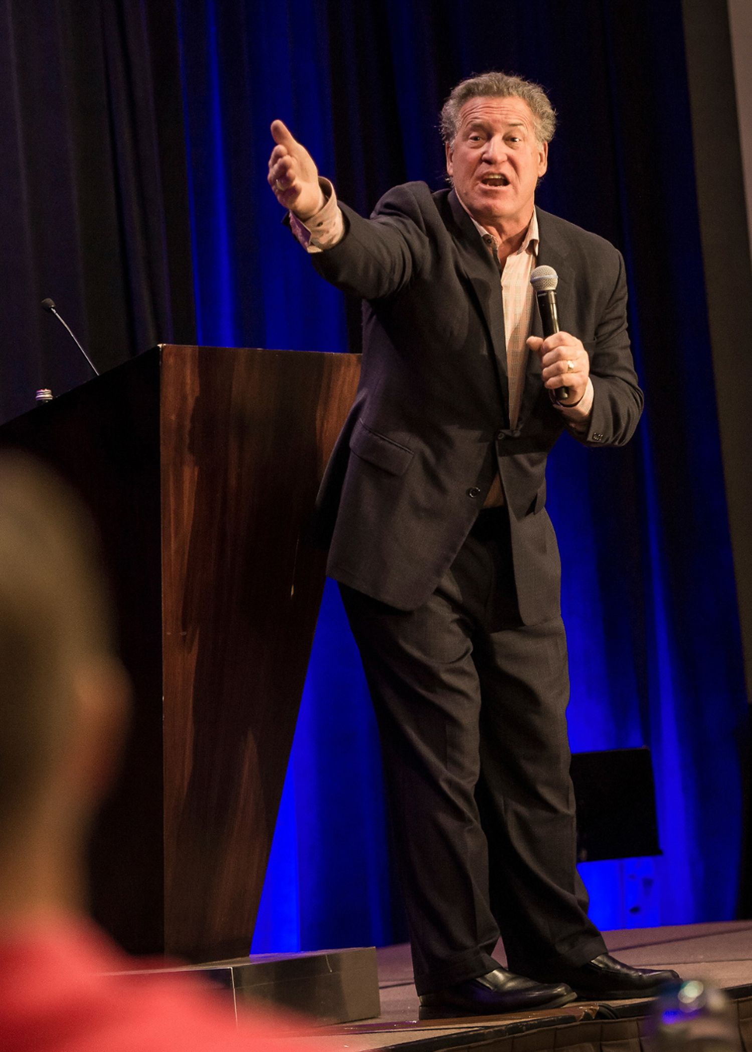 Man speaking onstage and gesturing to an audience.